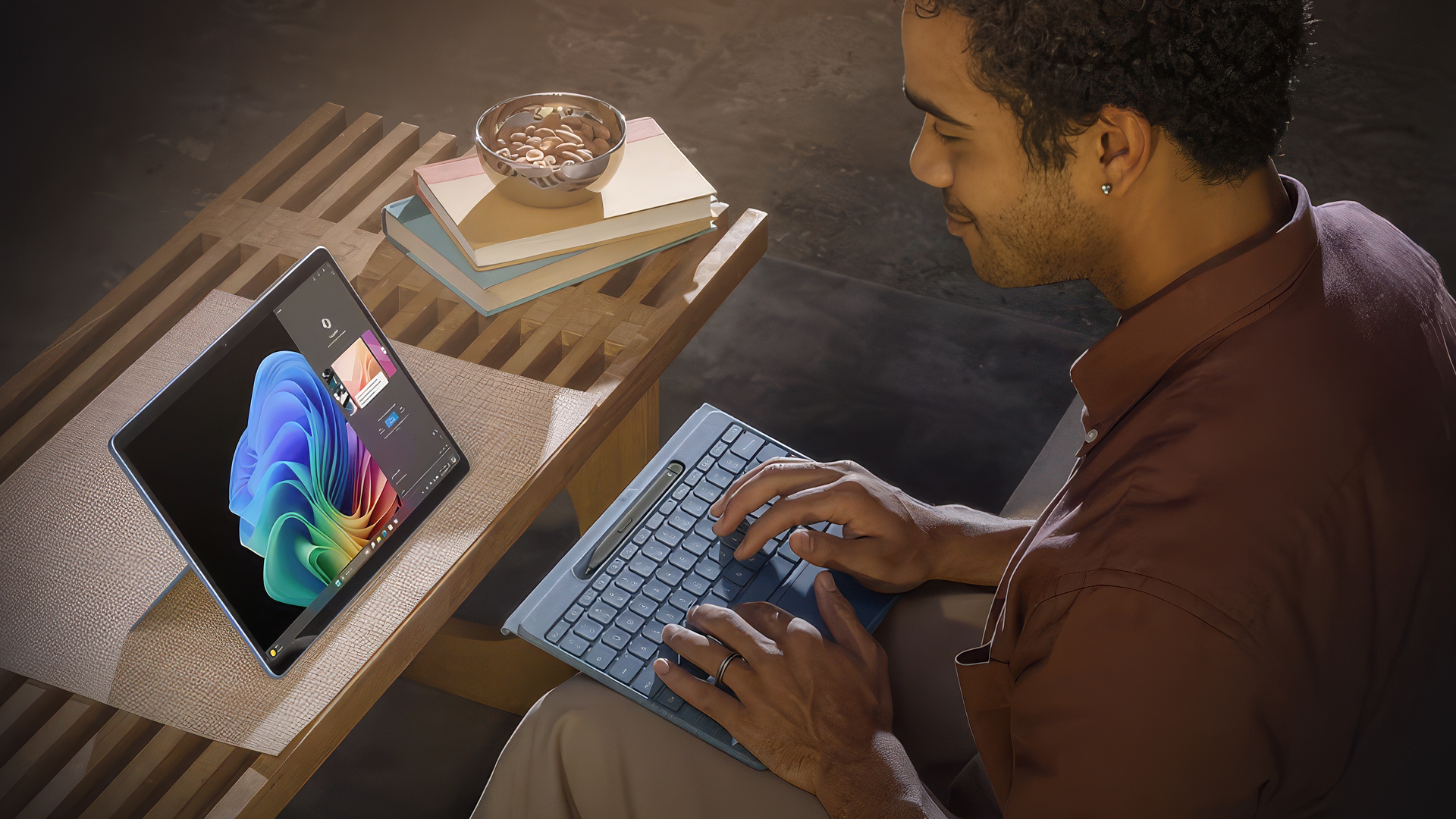 A smiling man typing on a Microsoft Surface Pro with a detachable keyboard.