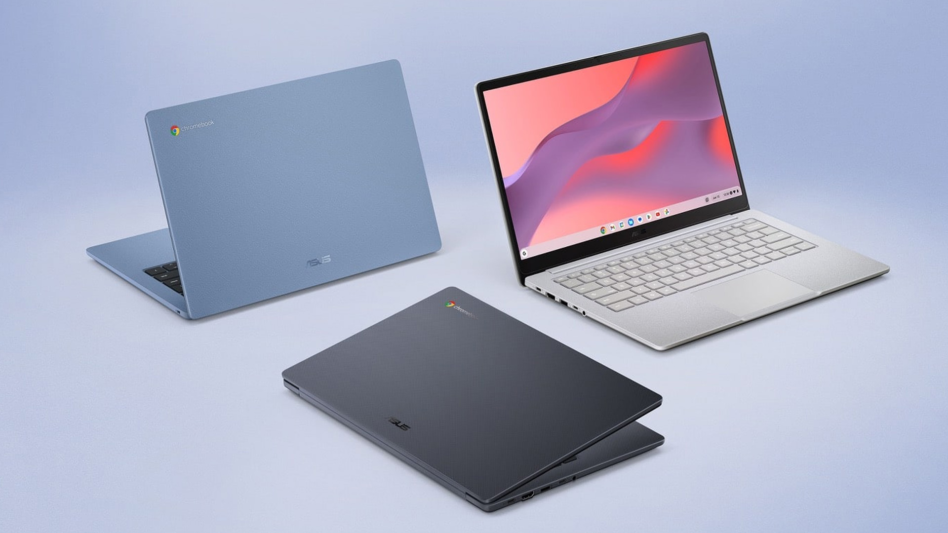 Three ASUS Chromebook laptops in blue, dark grey, and silver colors arranged on a light surface.