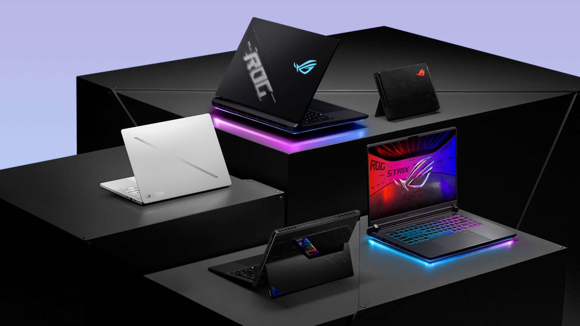 Multiple ASUS ROG gaming laptops displayed on dark geometric stands with RGB lighting.