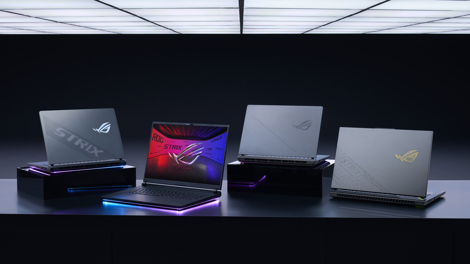 Multiple ASUS ROG Strix gaming laptops arranged with RGB lighting on a table.