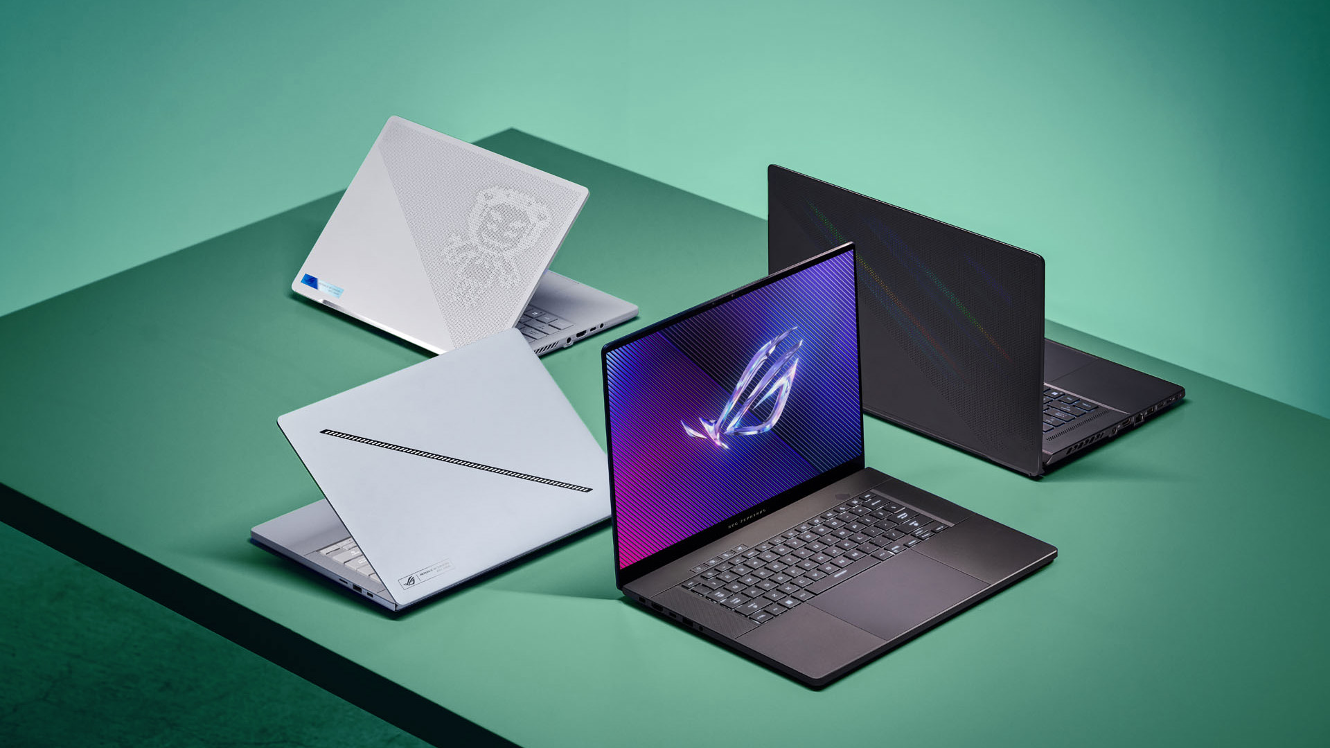 Four ASUS ROG Zephyrus gaming laptops arranged neatly on a smooth green surface.