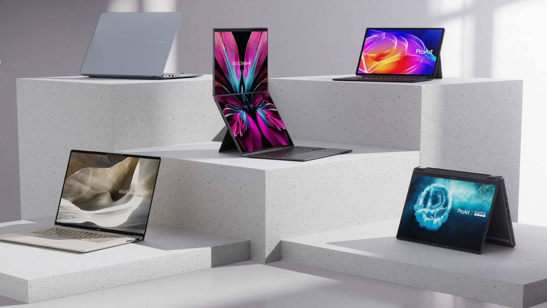 ASUS Zenbook and ProArt laptops displayed on geometric stone pedestals.