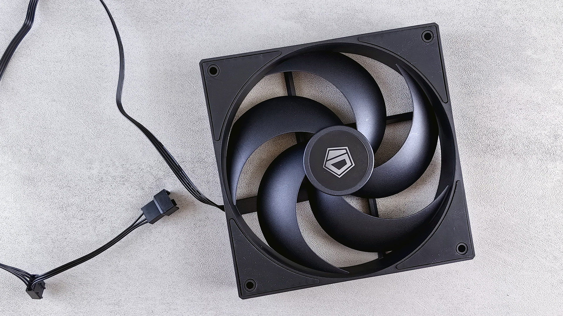 A black computer cooling fan resting on a clean neutral surface.