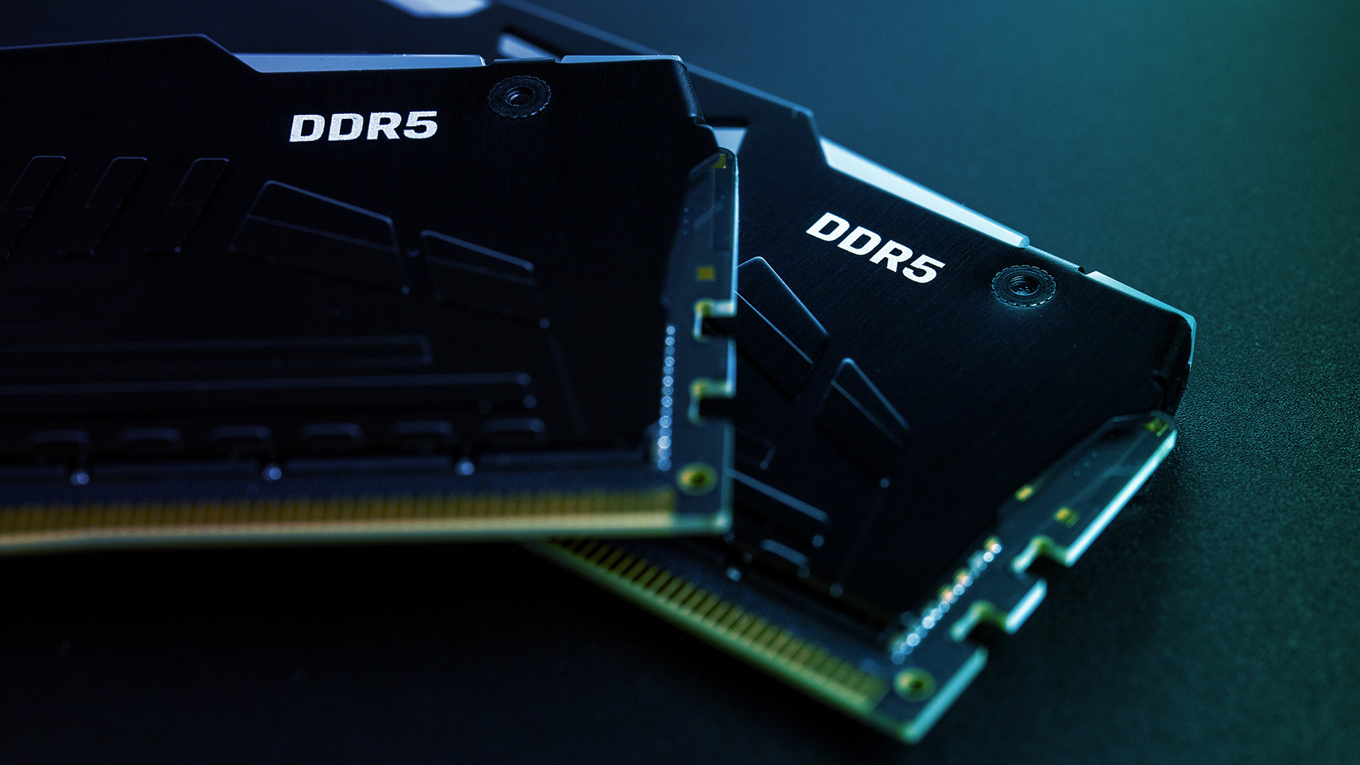 Two black DDR5 desktop memory modules resting on a dark, textured surface.