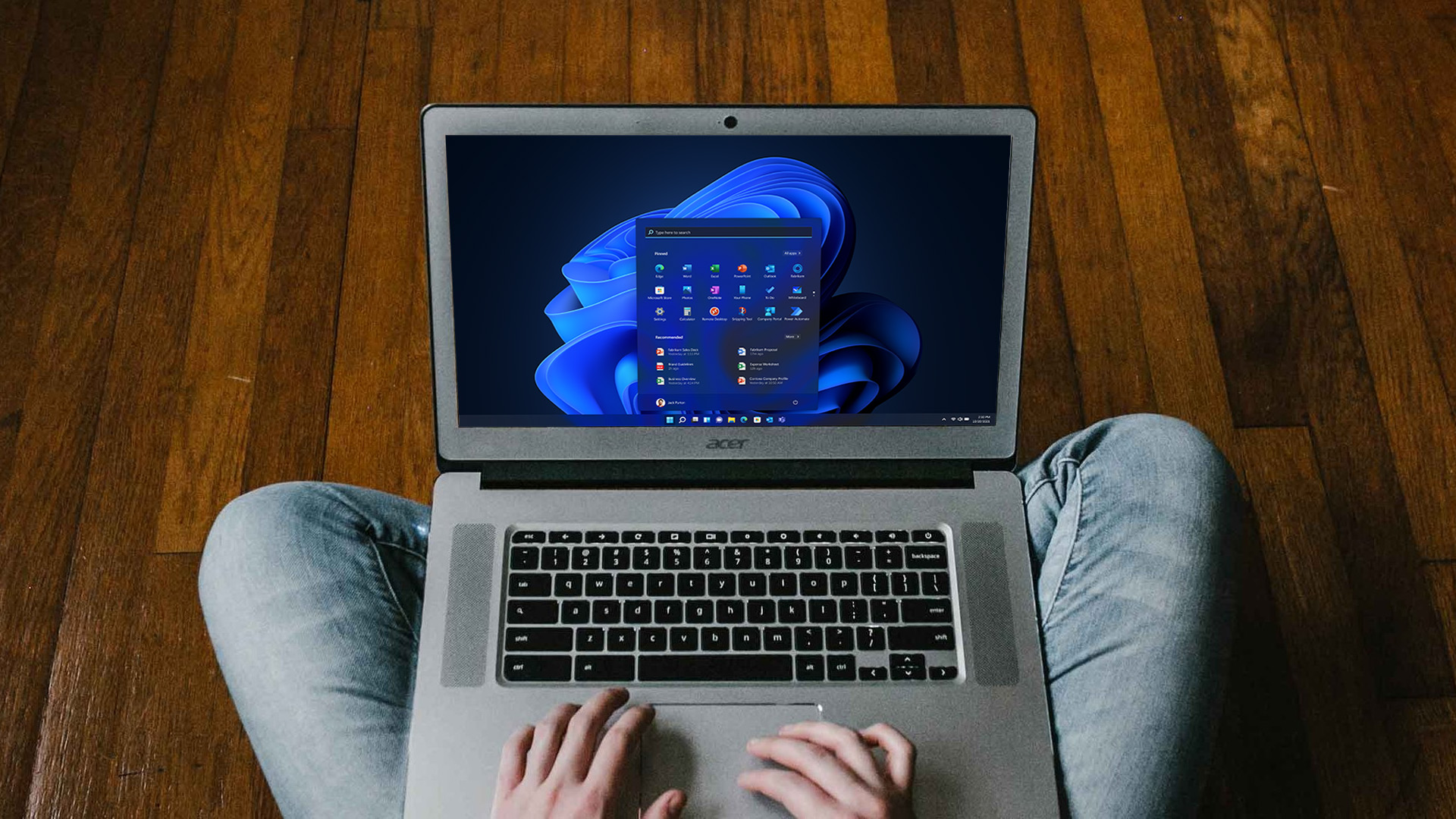 A person sitting with a Chromebook running the Windows 11 desktop environment.