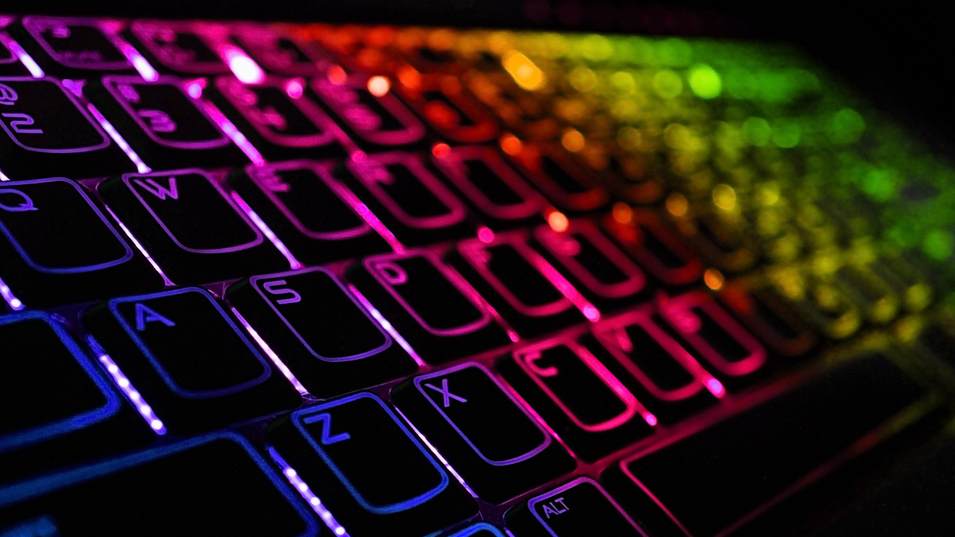 Close-up of flat membrane gaming keyboard keys illuminated by colorful RGB.