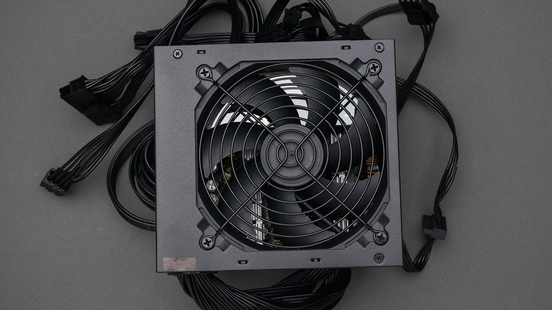 A close-up view of a power supply unit surrounded by its black power cables.