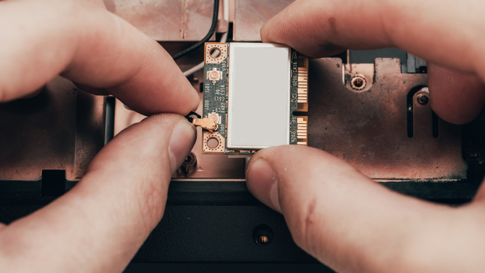 Connecting a tiny antenna cable to a laptop Wi-Fi card.