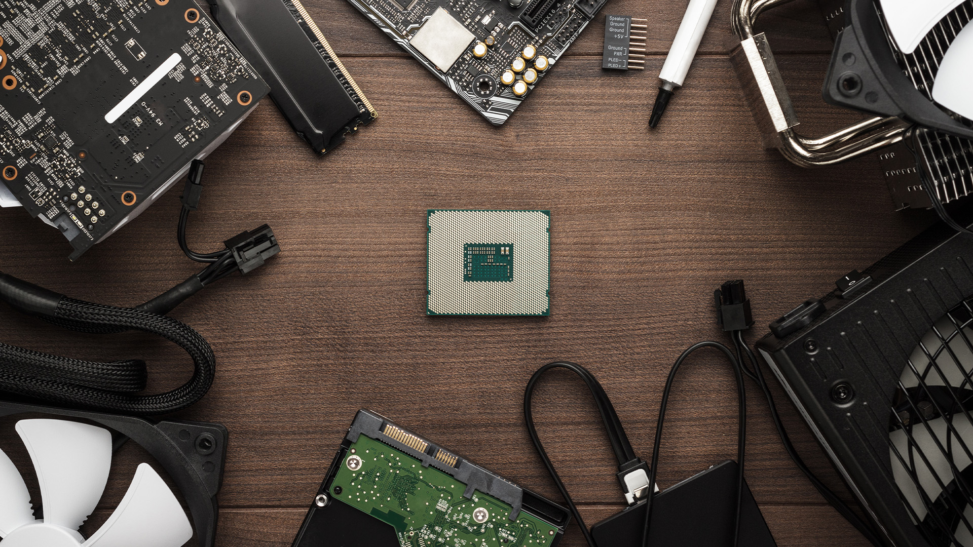 Various desktop PC build components like CPU and RAM arranged on a wooden table.