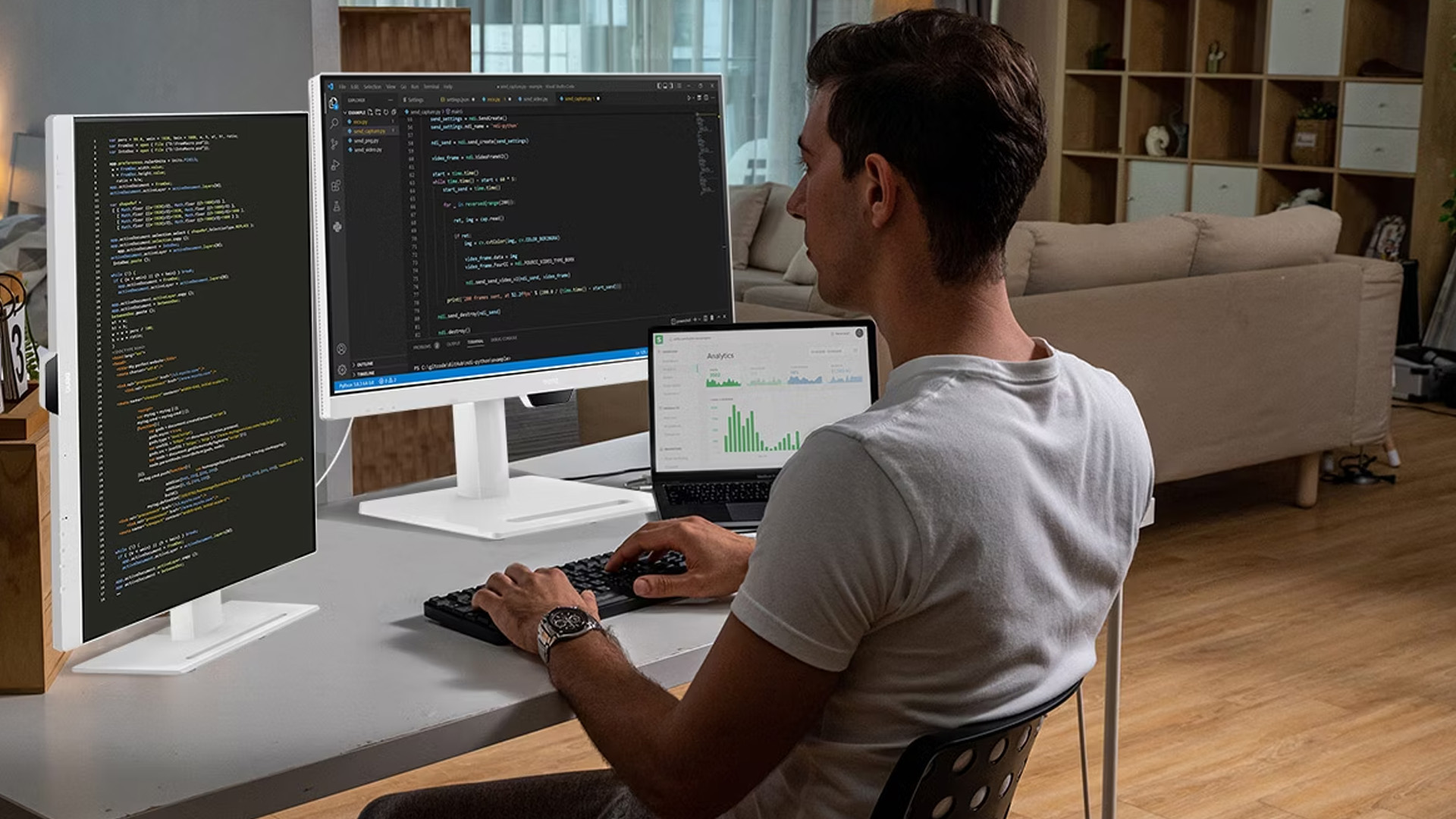Developer working on programming code with dual BenQ monitors and a laptop.