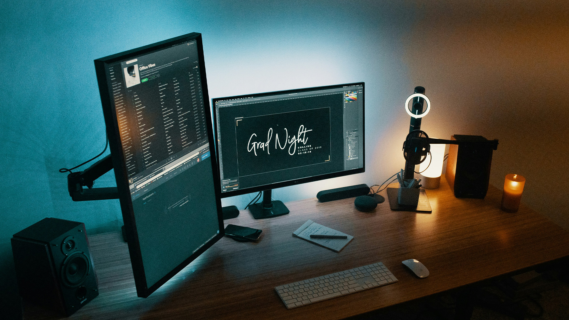 A dual-monitor workstation with a vertical screen playing music and a horizontal screen editing text.