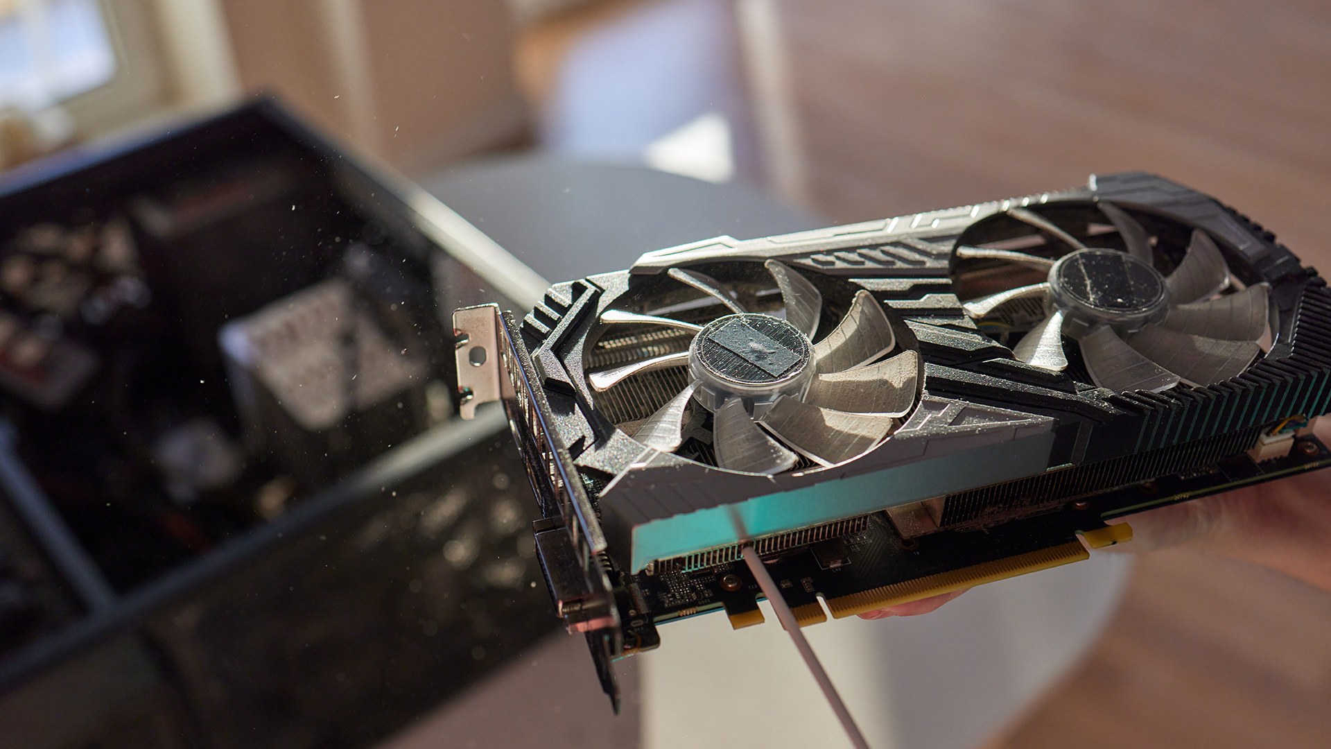 A dusty graphics card being held up for inspection and cleaning before installation.