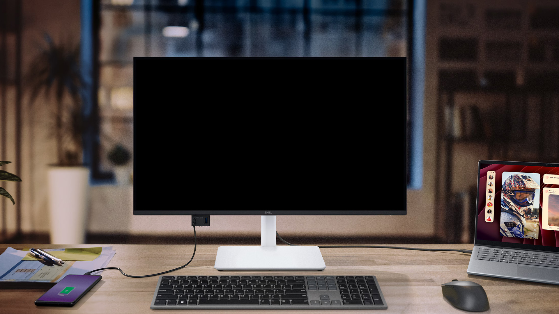 Dell monitor with a blank black screen connected to a laptop on a desk.
