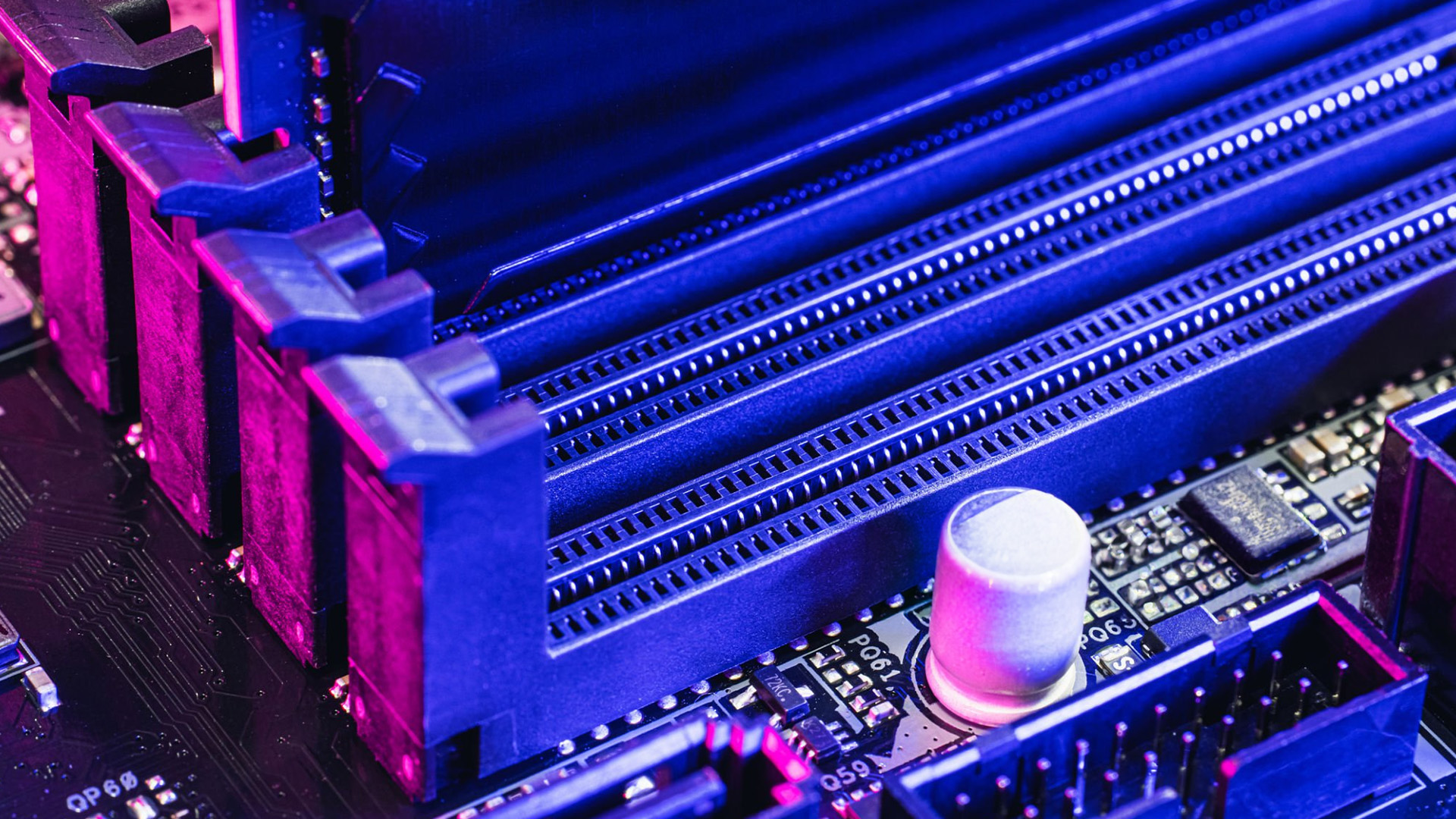 Close-up of empty RAM slots on a computer motherboard under purple and blue lighting.