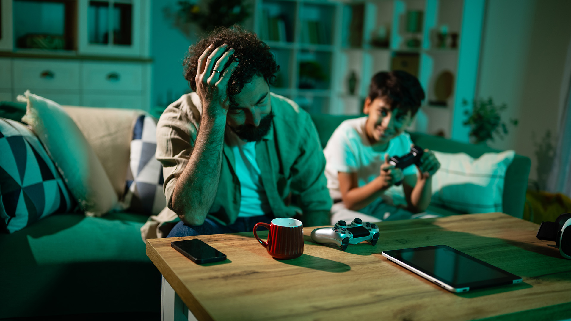 Frustrated man sitting on a couch while a boy plays a video game.