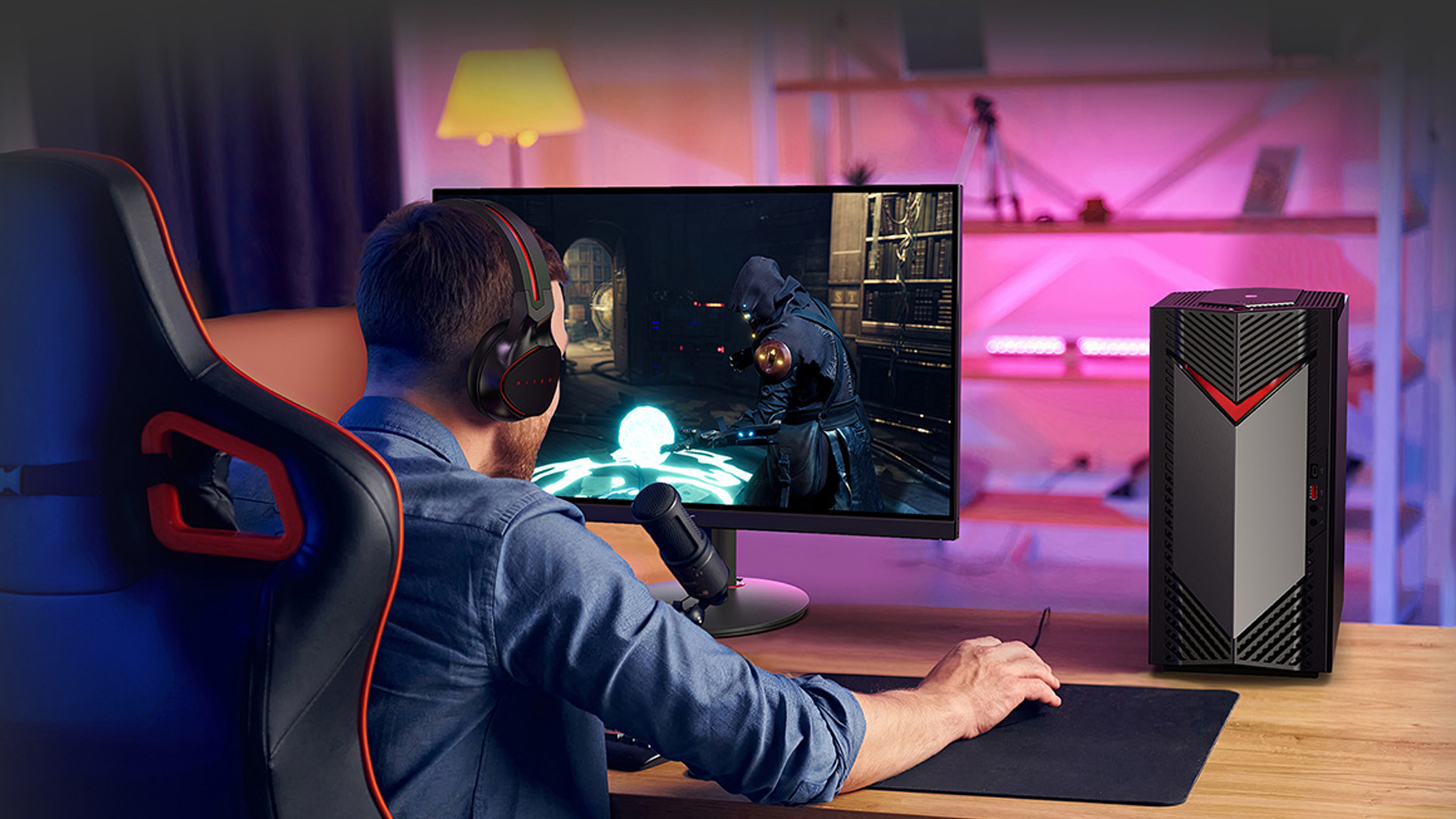 A gamer wearing a headset playing a video game at a wooden desk with an Acer gaming desktop tower.