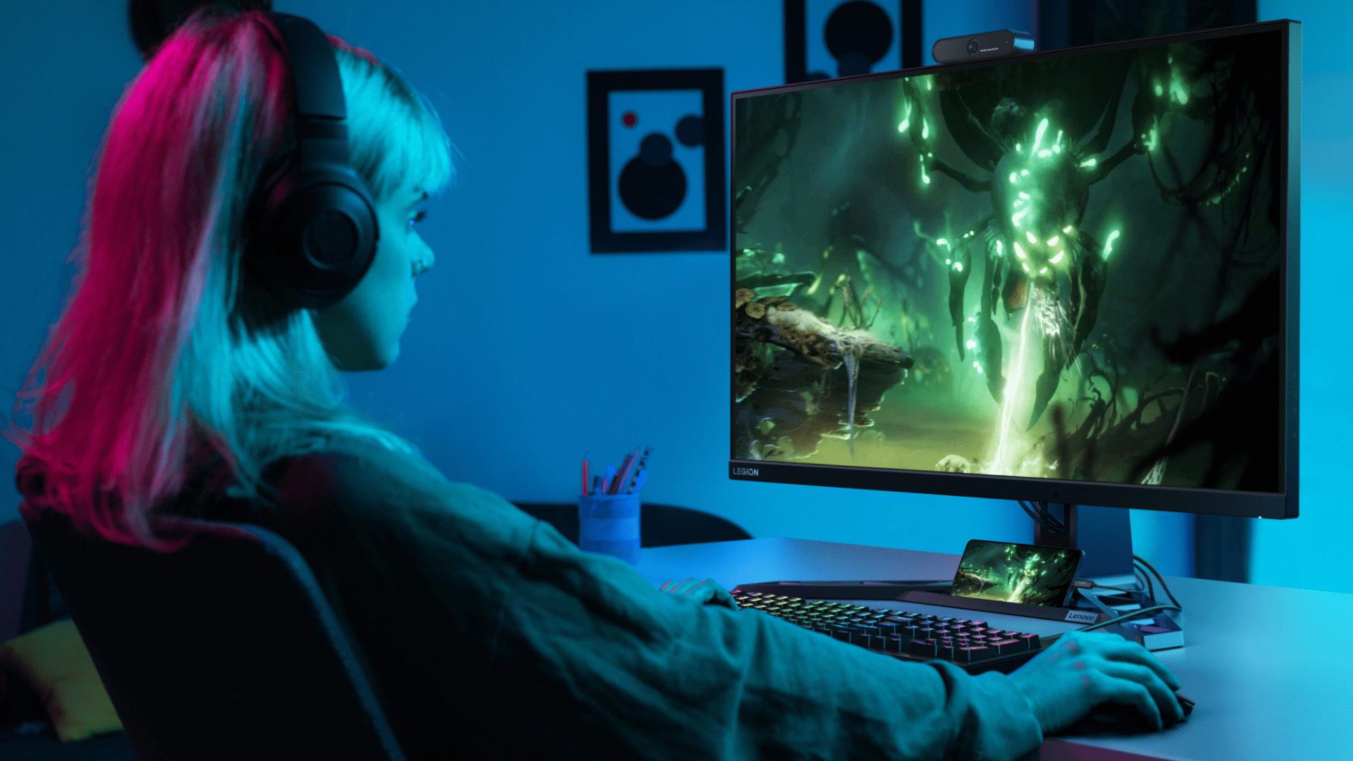 Gamer wearing headphones playing on a Lenovo Legion gaming monitor.