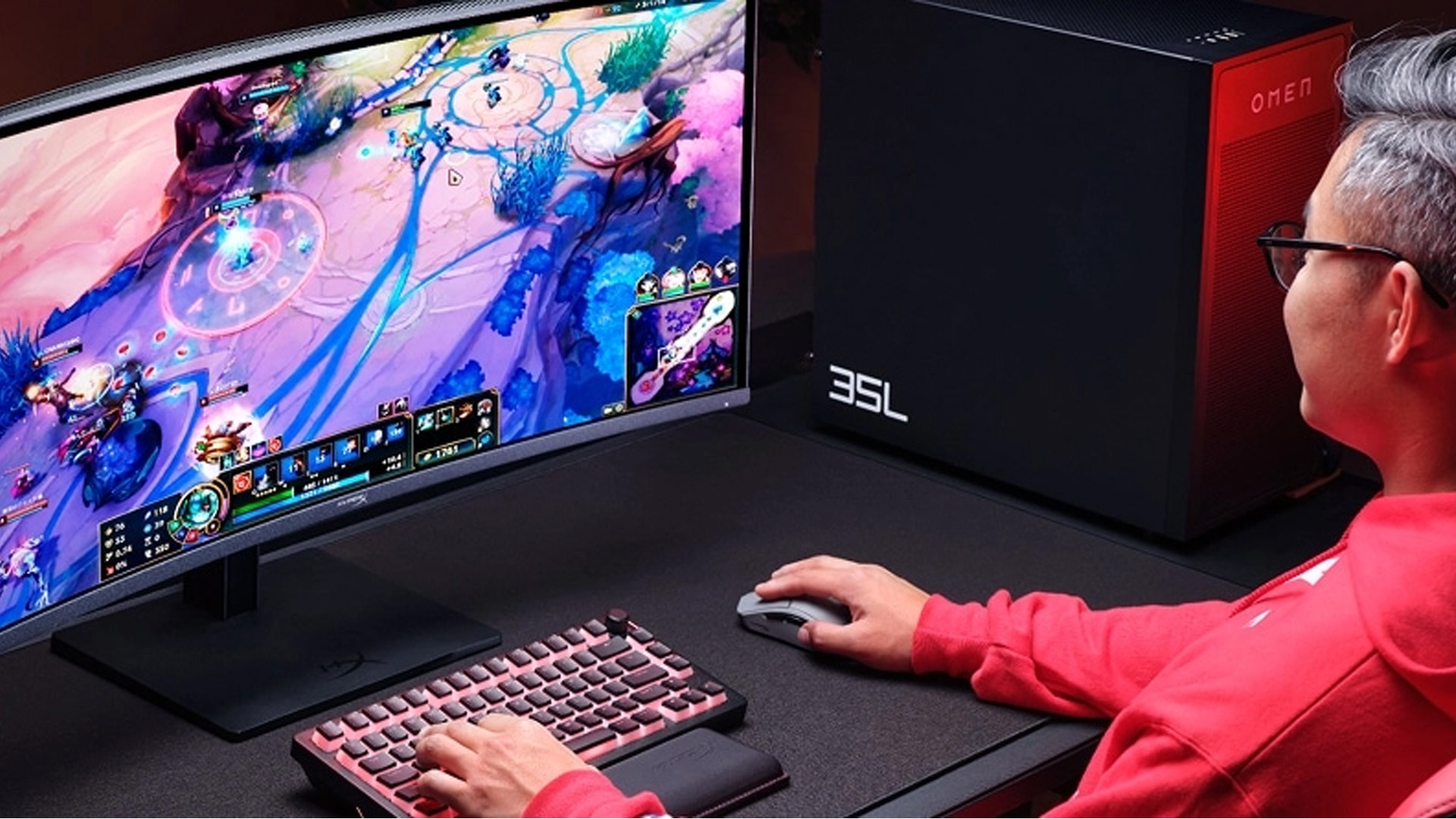 Gamer playing a MOBA game on a gaming monitor beside an HP OMEN desktop.