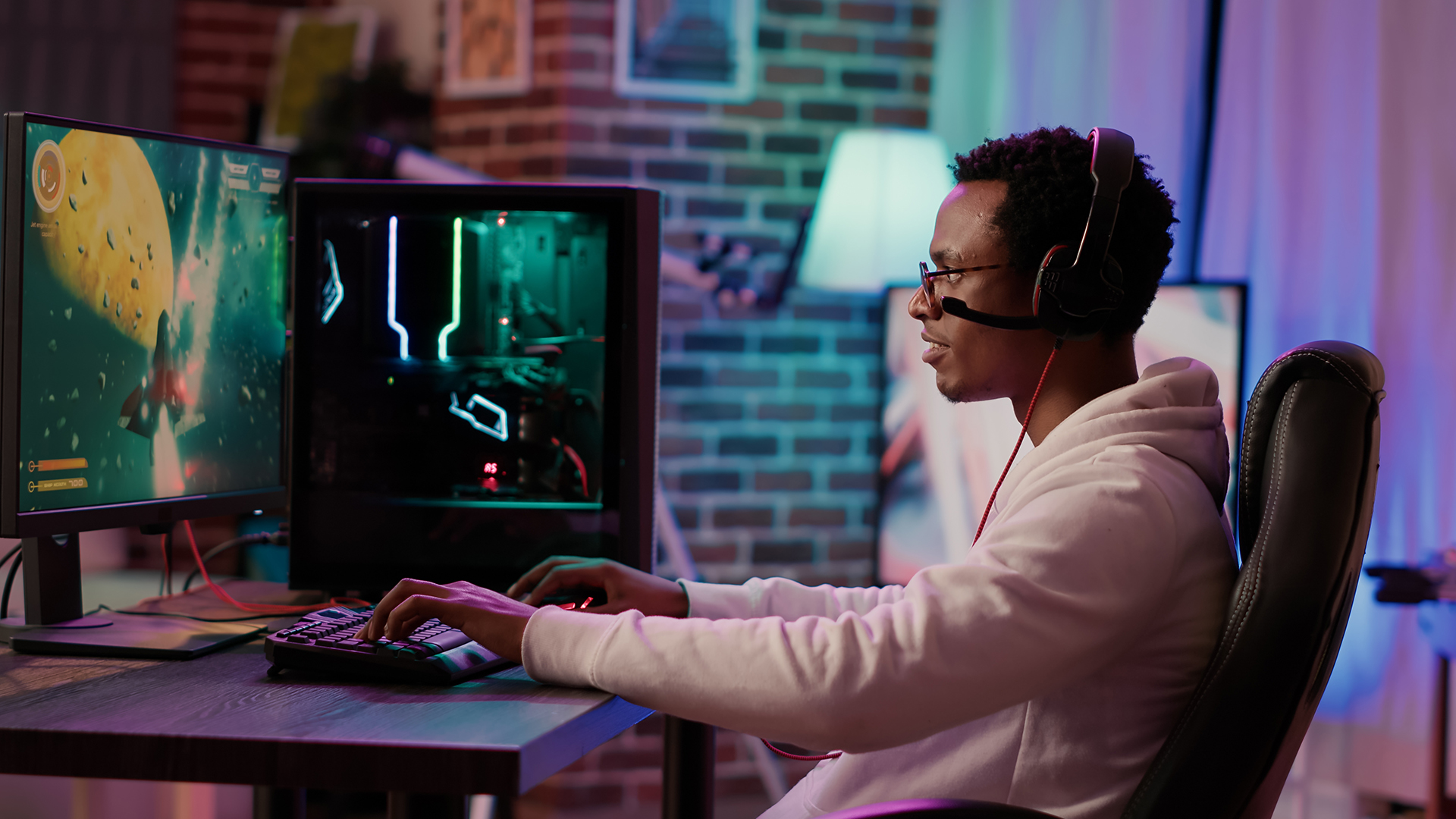 A young man wearing a headset while playing a space game on his PC.