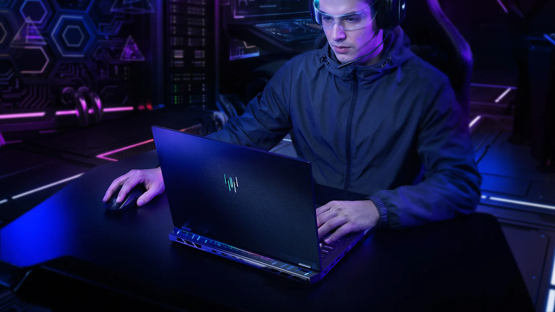 Gamer wearing headset typing on an Acer Predator Helios laptop at a gaming desk.