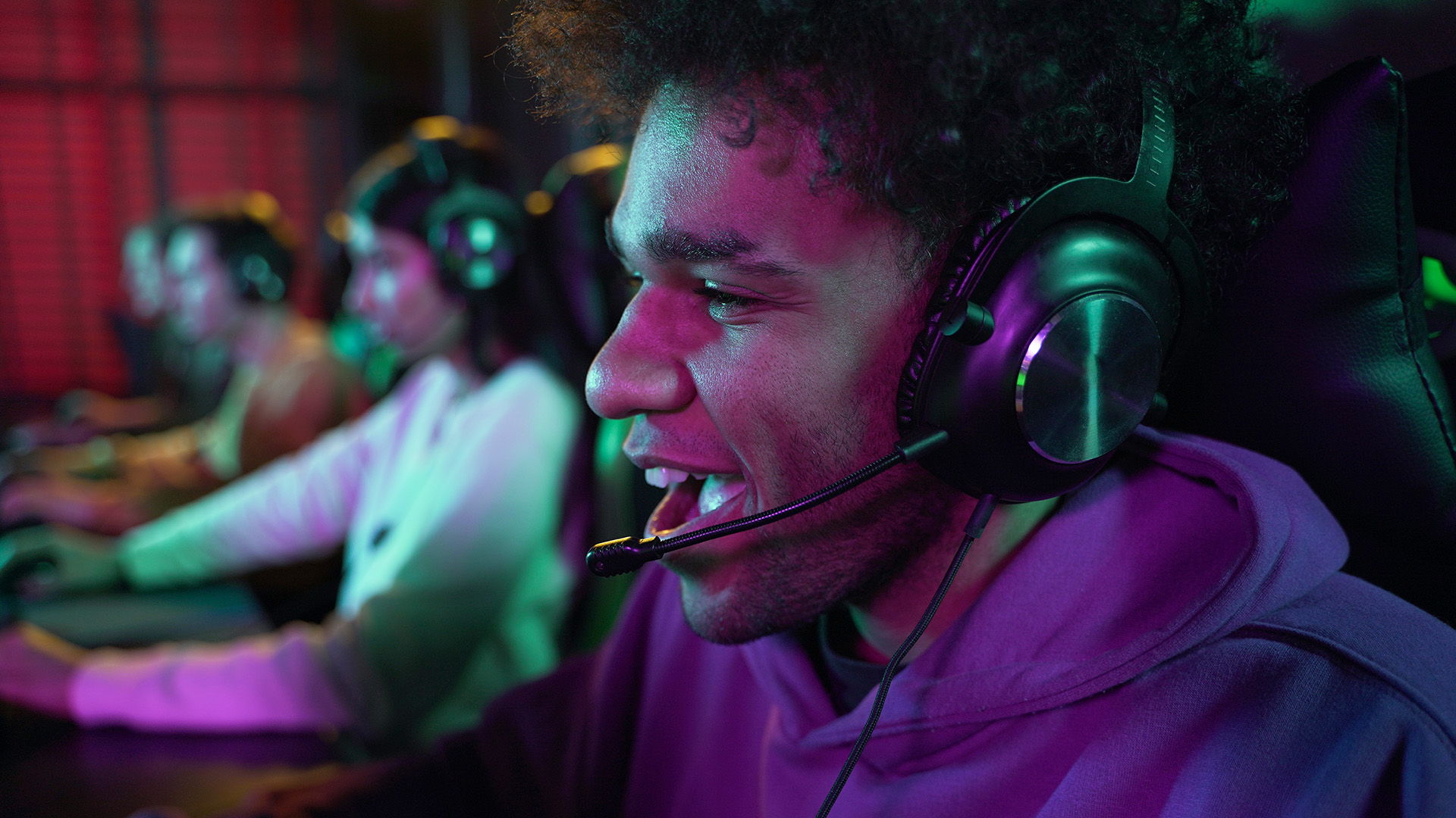 Young gamer wearing a headset with a boom mic, smiling during a multiplayer session.