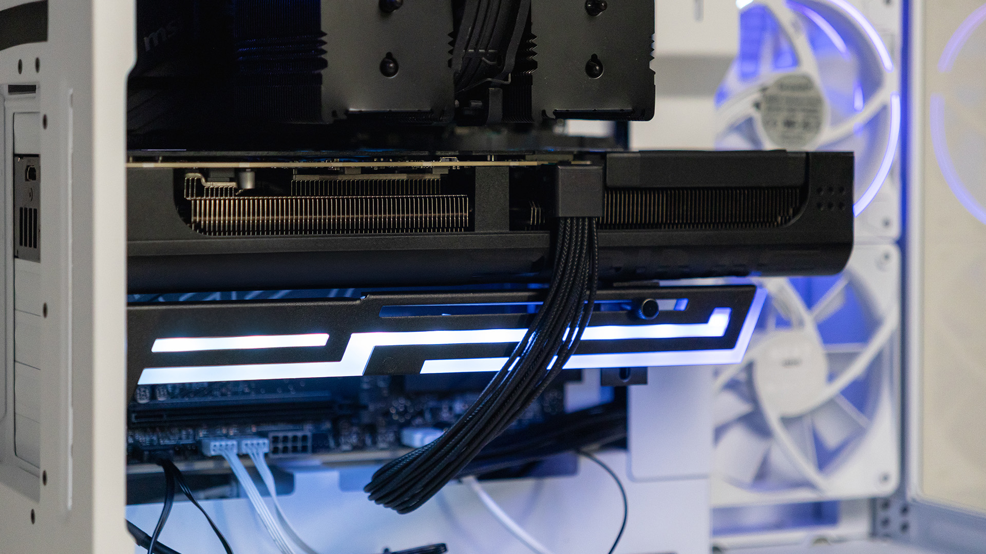 A heavy graphics card supported by an anti-sag bracket inside a white PC chassis.