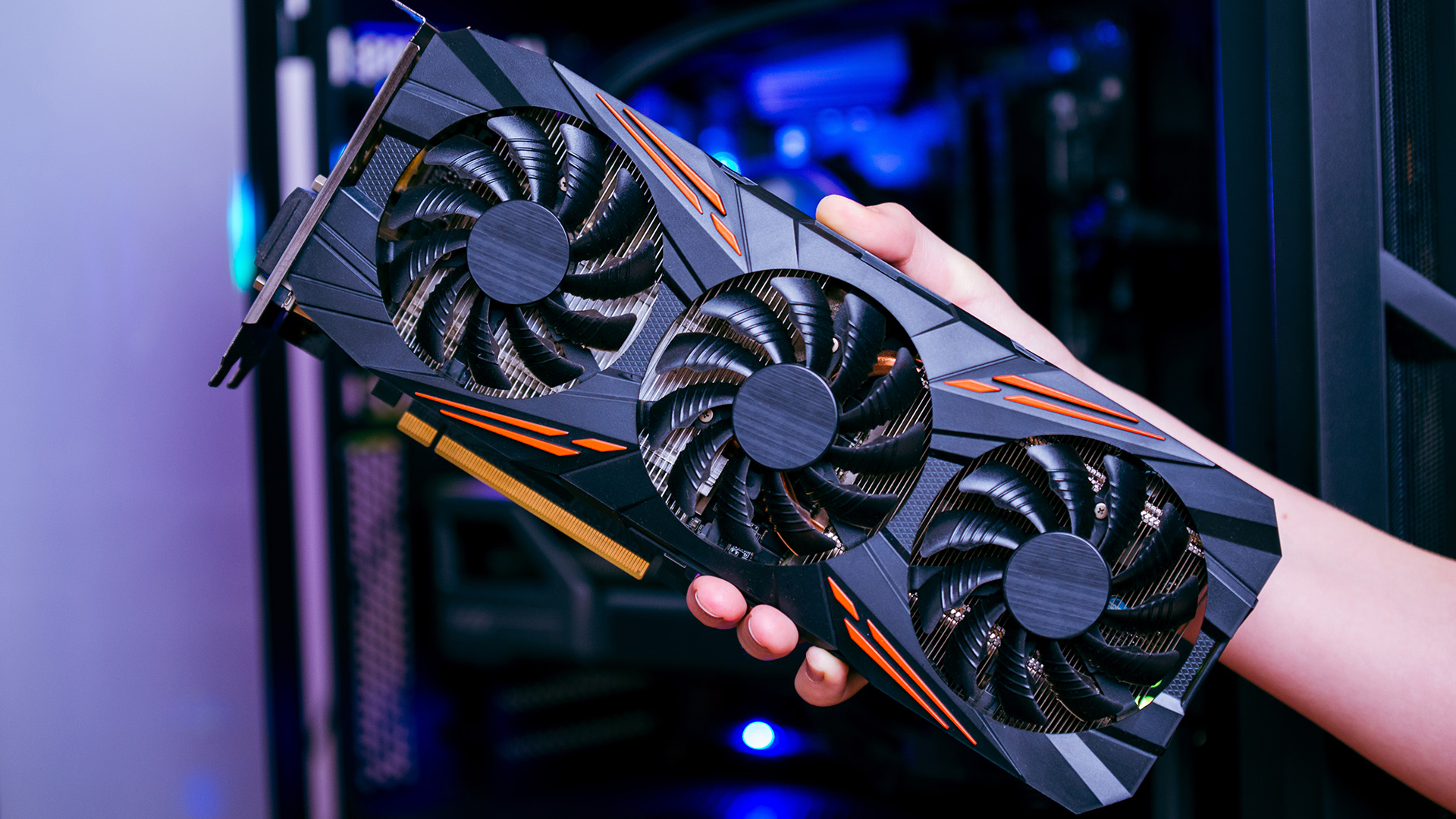 A hand holding a triple-fan high-end graphics card designed for 4K gaming.