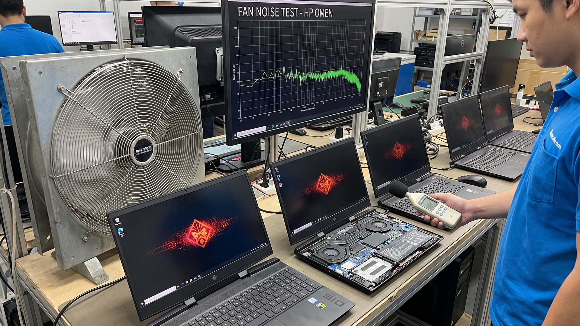 Technician using a decibel meter to test HP OMEN laptop fan noise in a lab.