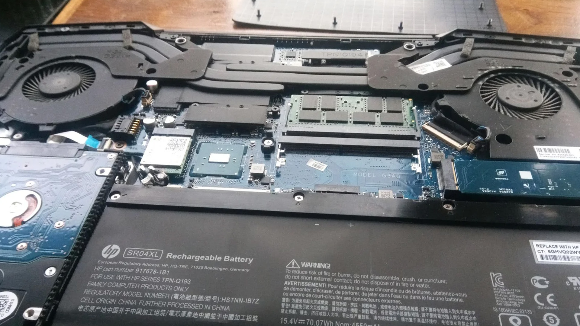 Internal view of an HP laptop showing dual cooling fans and battery.