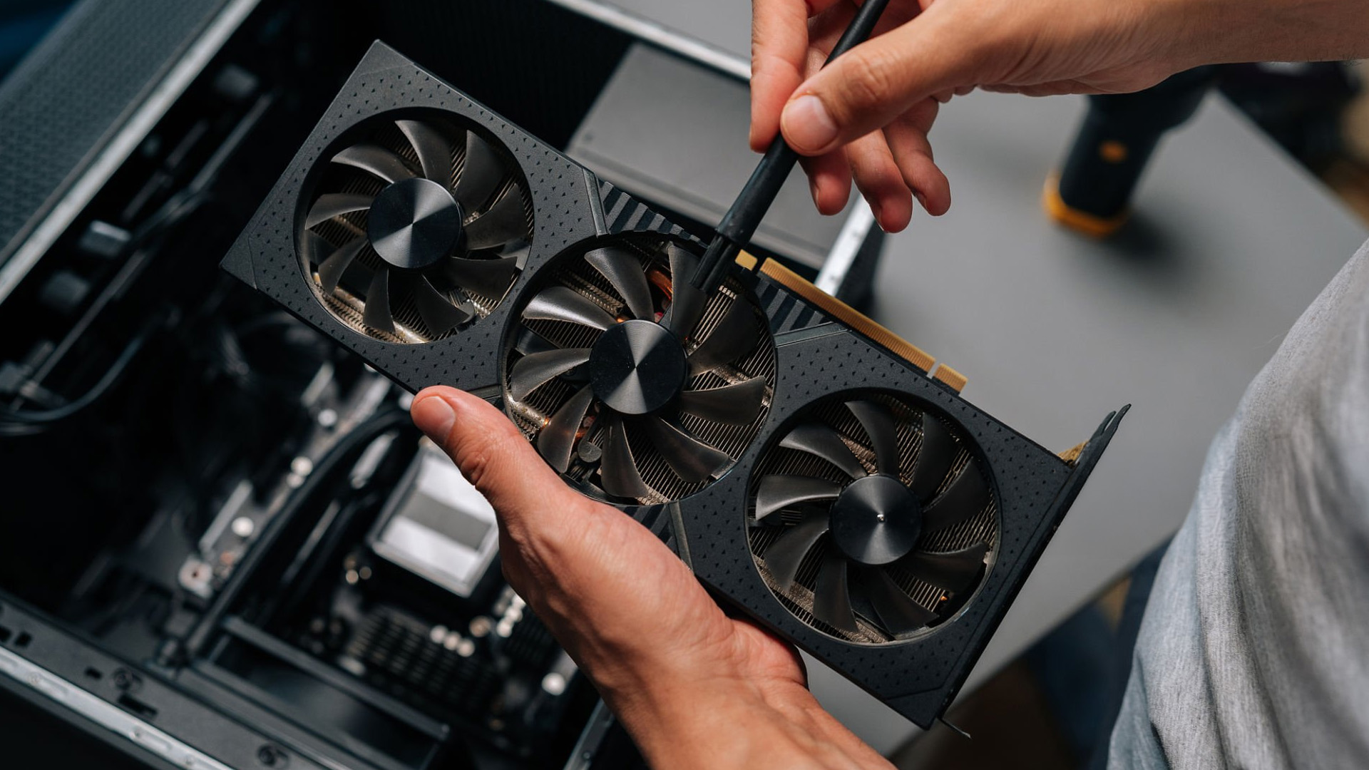 Inspecting graphics card fan blades for dust and debris.
