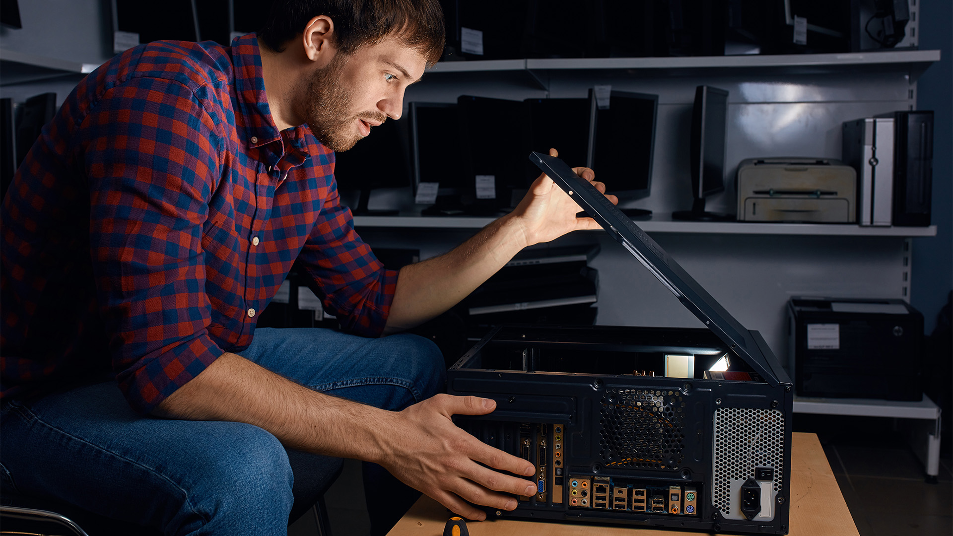 A man looking inside an open computer chassis on a workbench during a rebuild.