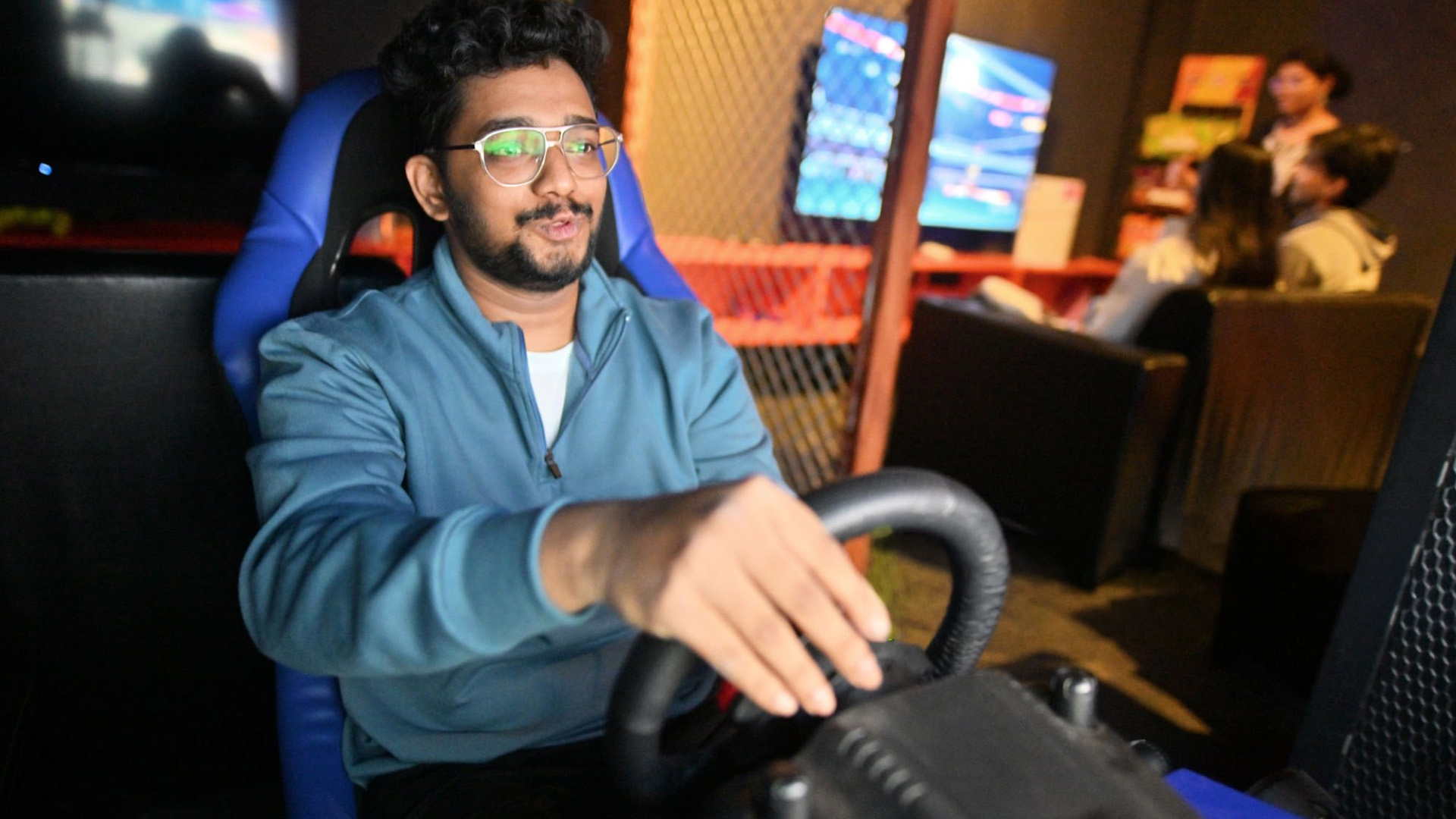 A young man sitting in a simulator rig playing a racing game.