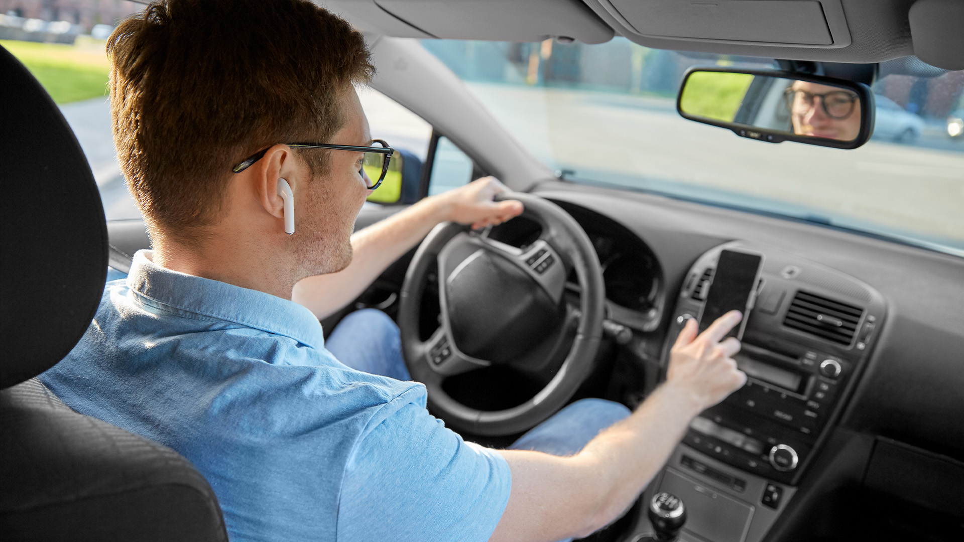 Man using wireless earbuds for hands-free calls while driving.