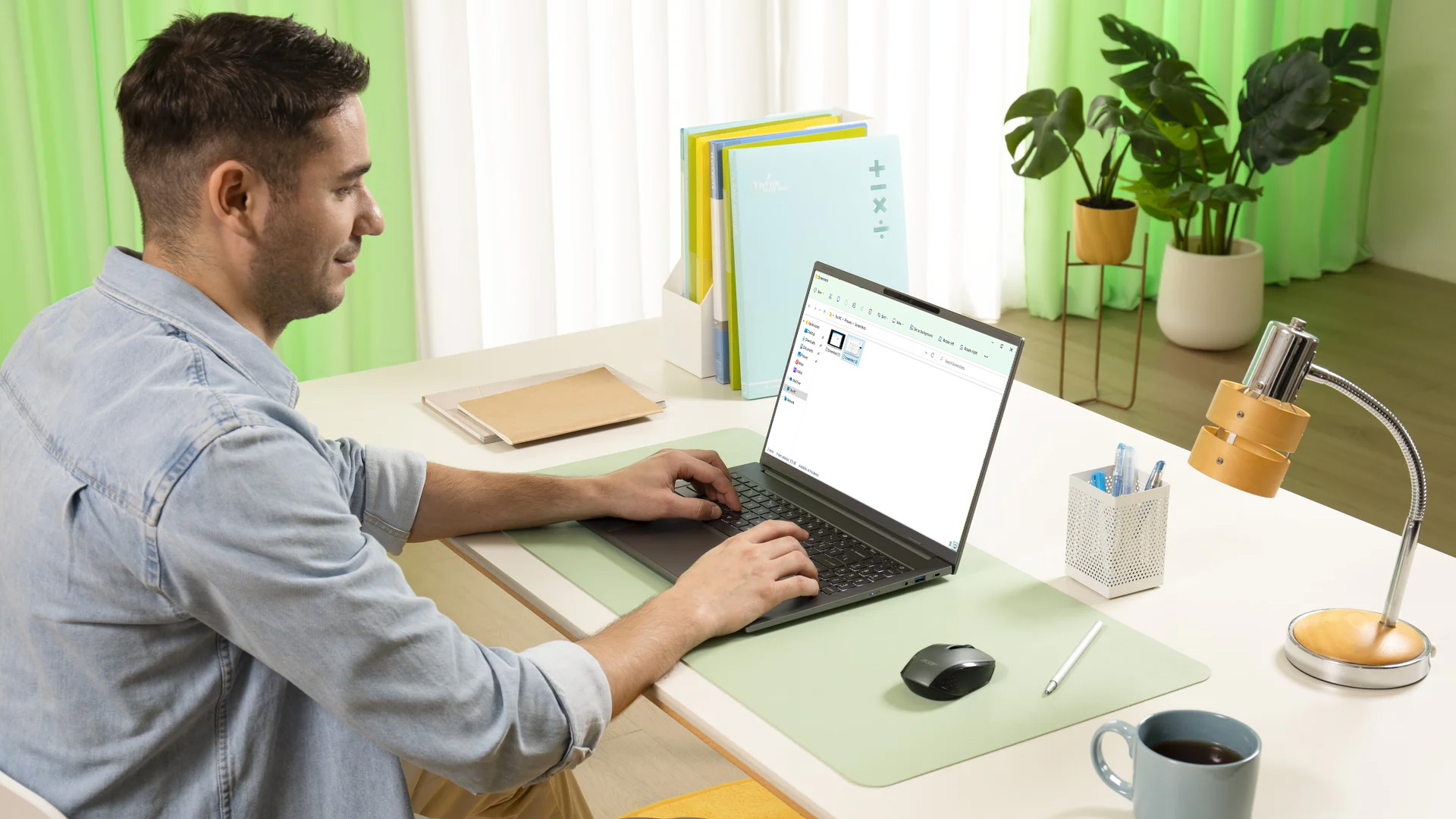 Man at a desk using an Acer laptop, viewing saved screenshots in File Explorer.