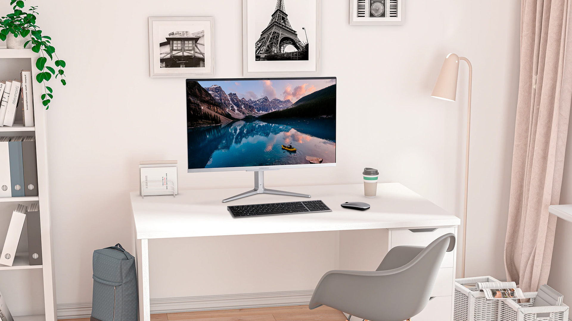 A Medion all-in-one PC displaying a nature landscape, set up on a clean white desk in a bright home office.