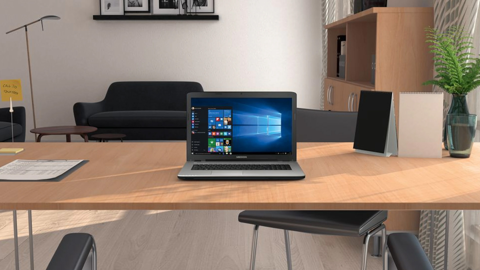 Open Medion laptop displaying Windows 10 on a wooden desk in an office.
