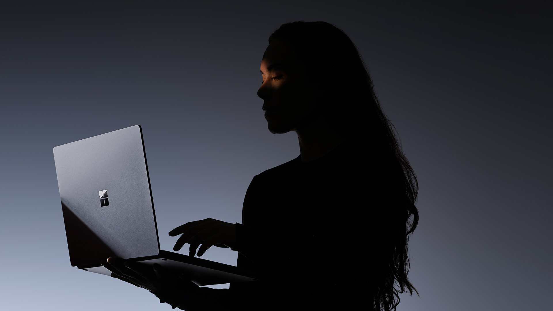 Silhouette of a person holding the new Microsoft Surface Laptop Ultra in the dark.