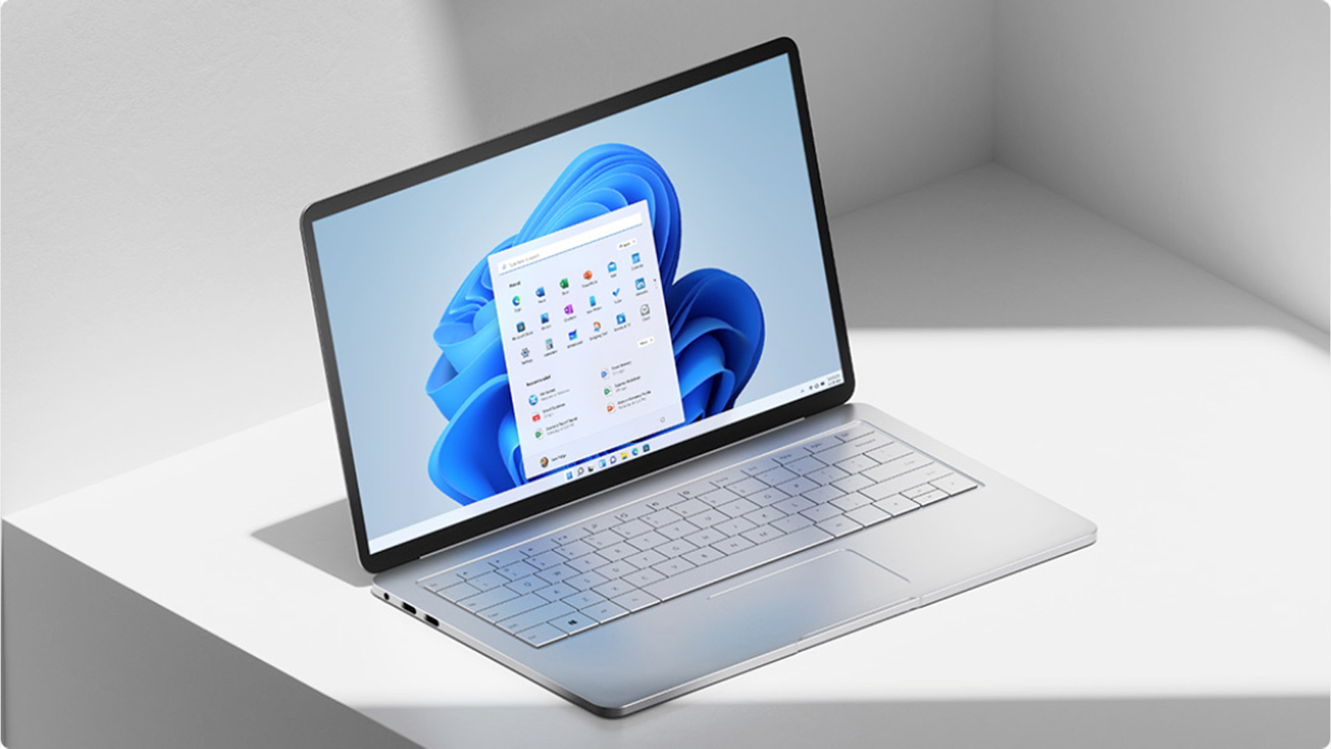 A modern Windows 11 laptop displaying the default desktop screen on a white desk.