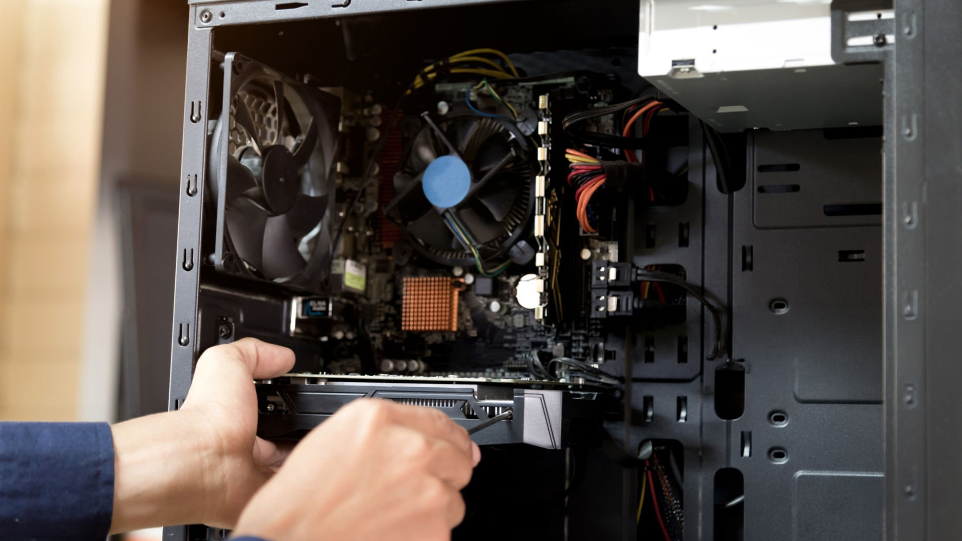 A person's hands installing a graphics card into a motherboard inside a computer case.