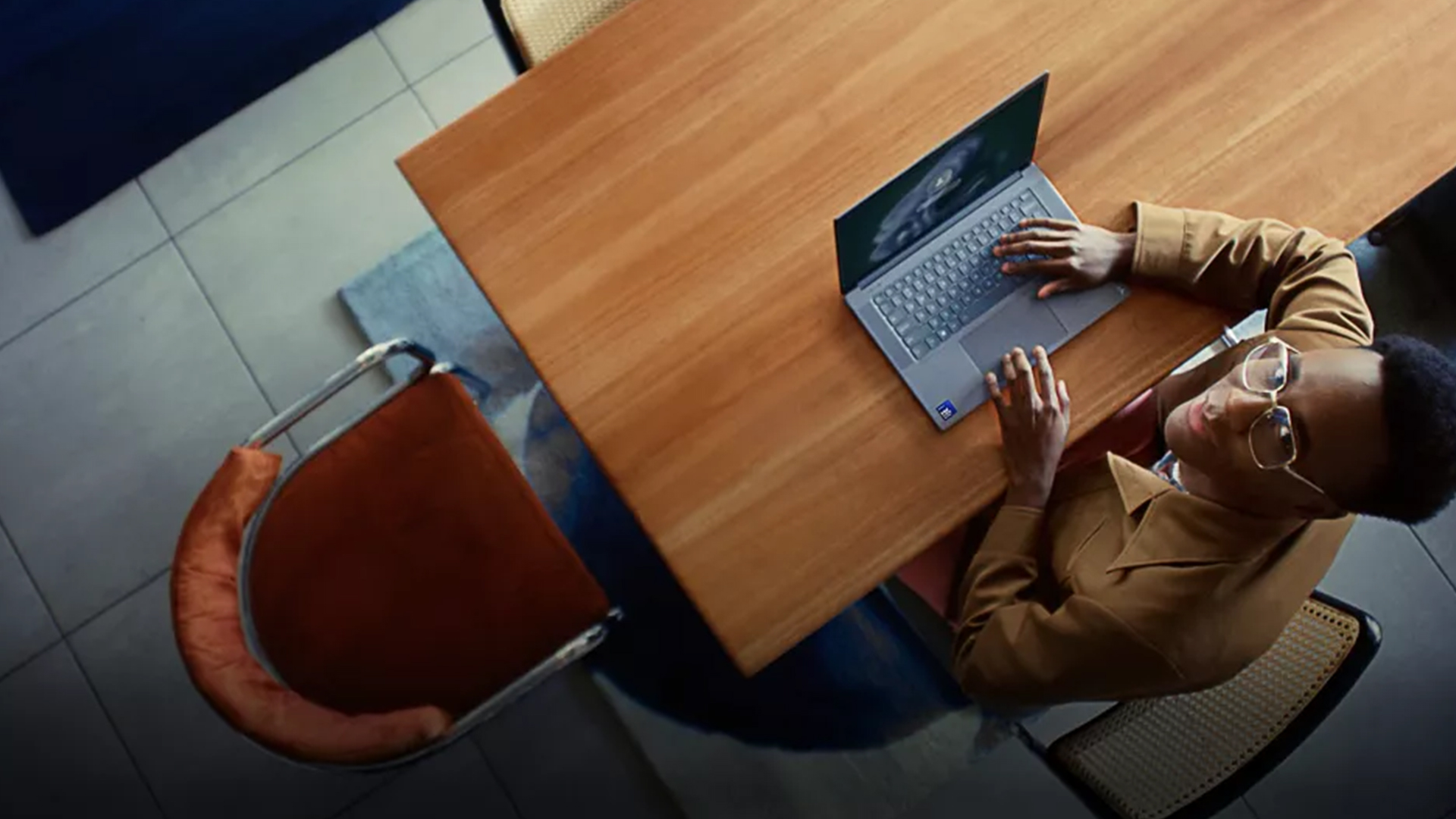 Overhead view of a person typing on a laptop at a wooden table.