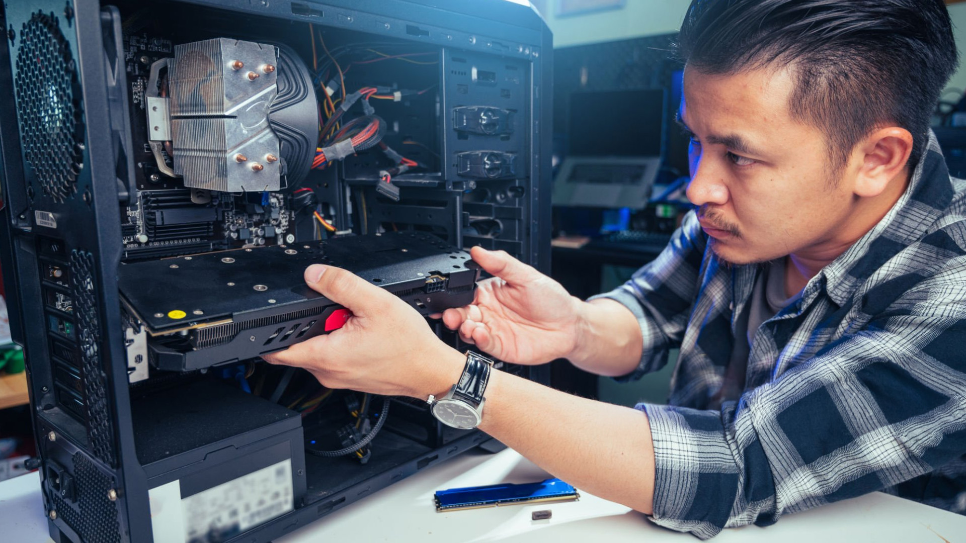 A PC builder carefully installing a graphics card horizontally into a motherboard slot.