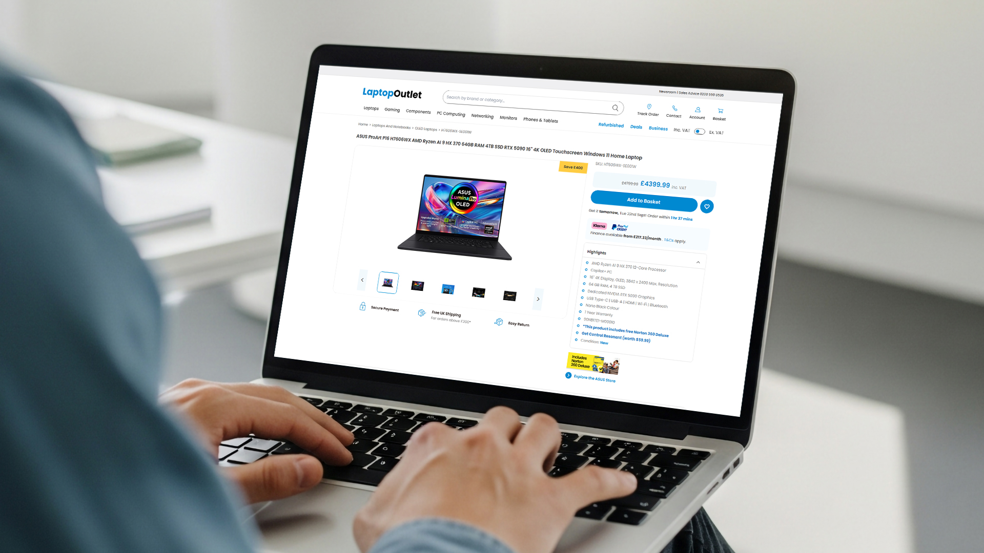 A person's hands typing on a laptop displaying an ASUS ProArt product page.