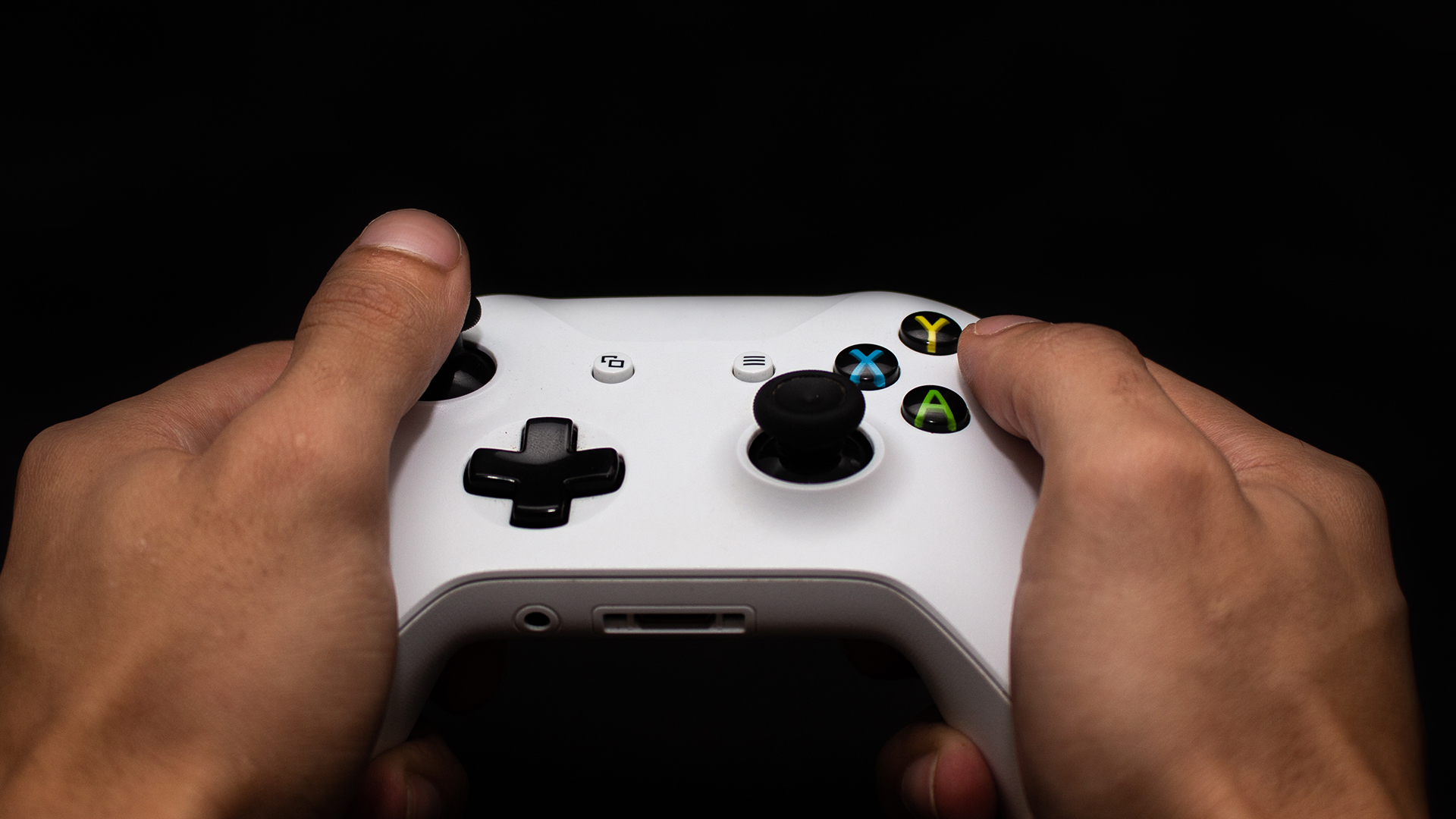 Person holding a white Xbox wireless controller while gaming.