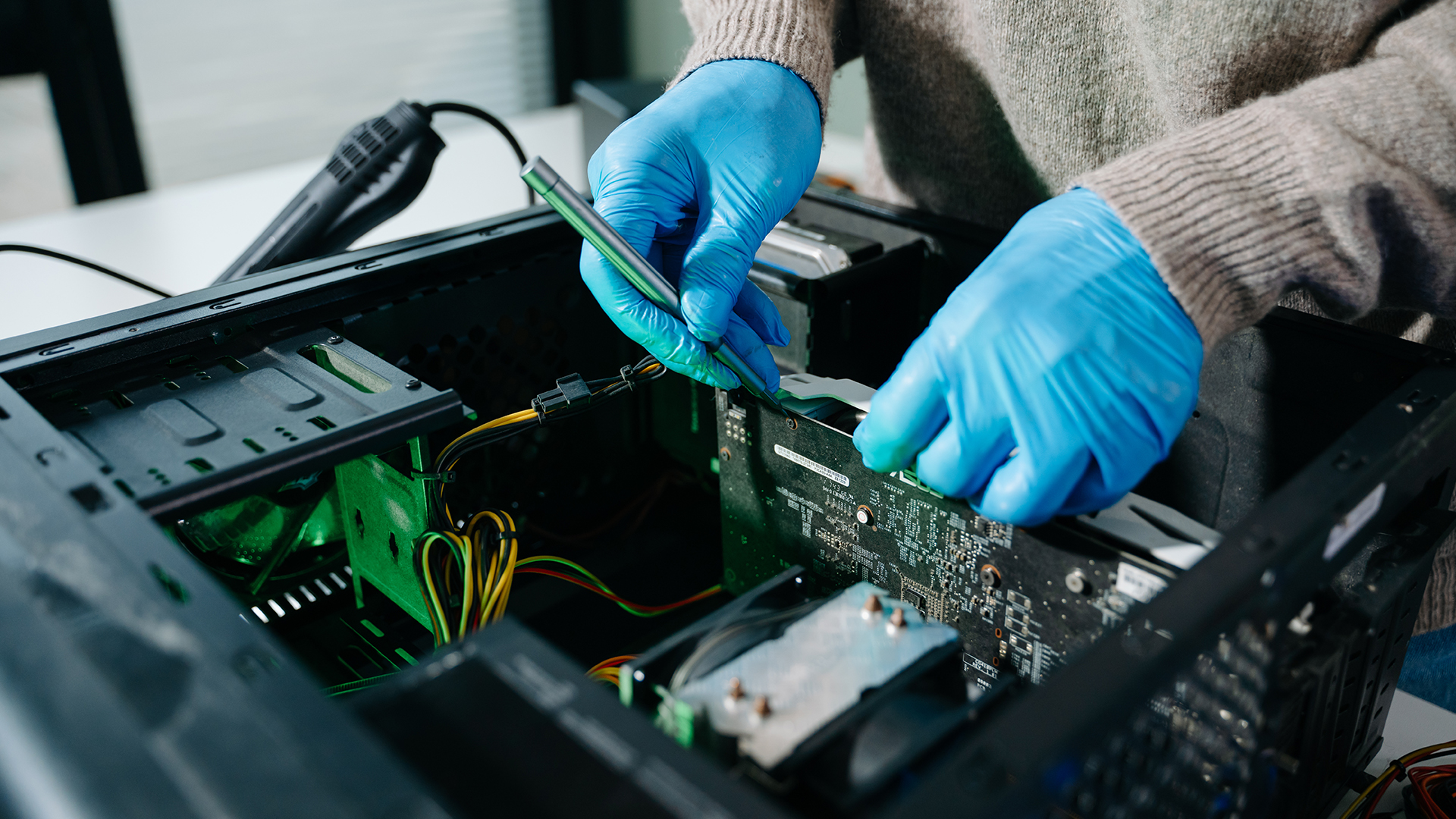 A person wearing blue gloves installing or adjusting components inside a desktop PC.