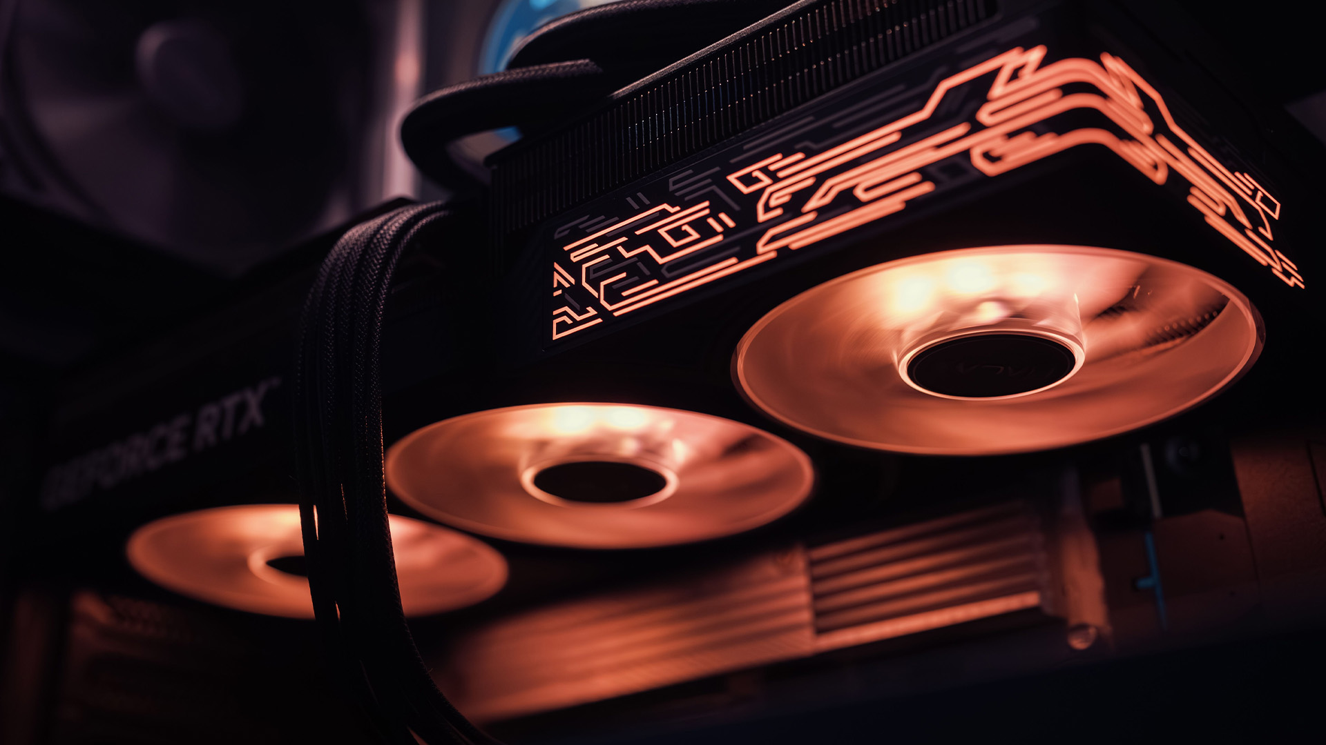 Close-up of a premium RTX graphics card with glowing orange fans installed inside a gaming PC.