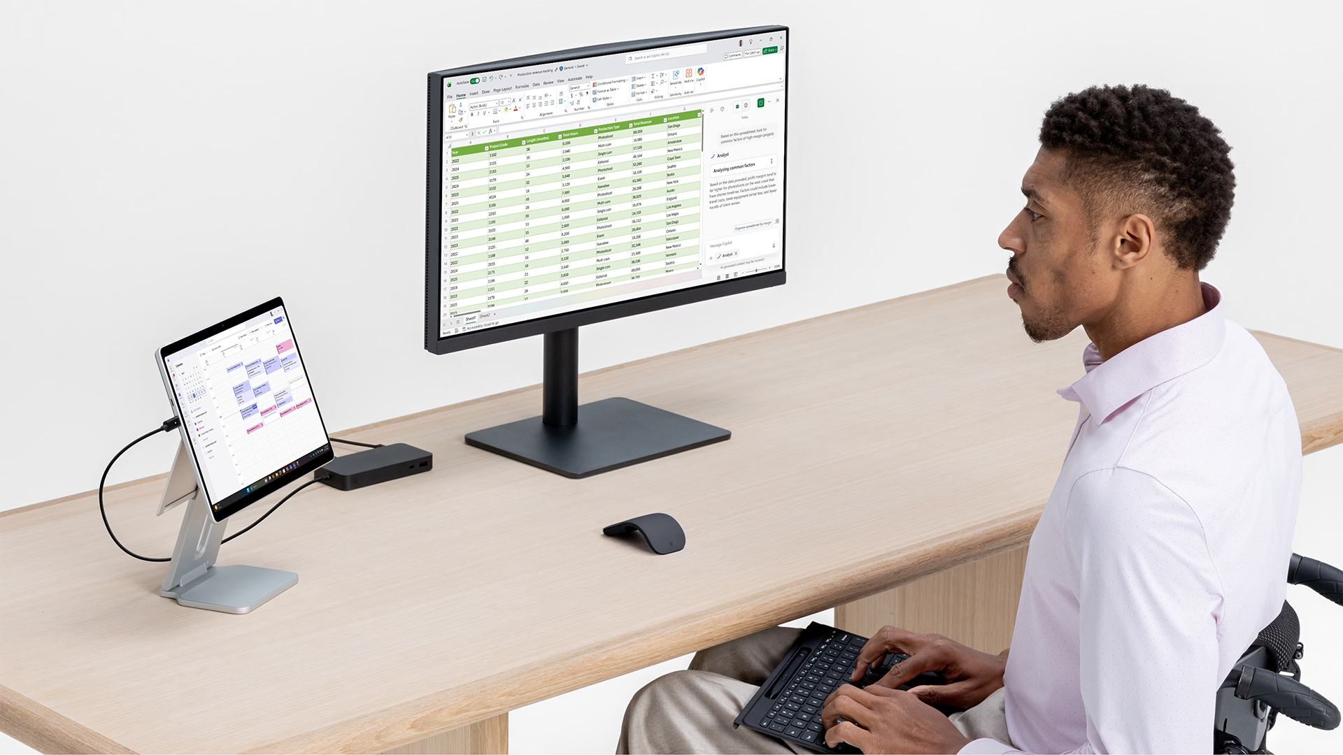 A professional working at a desk with a Surface Pro connected to a large monitor.