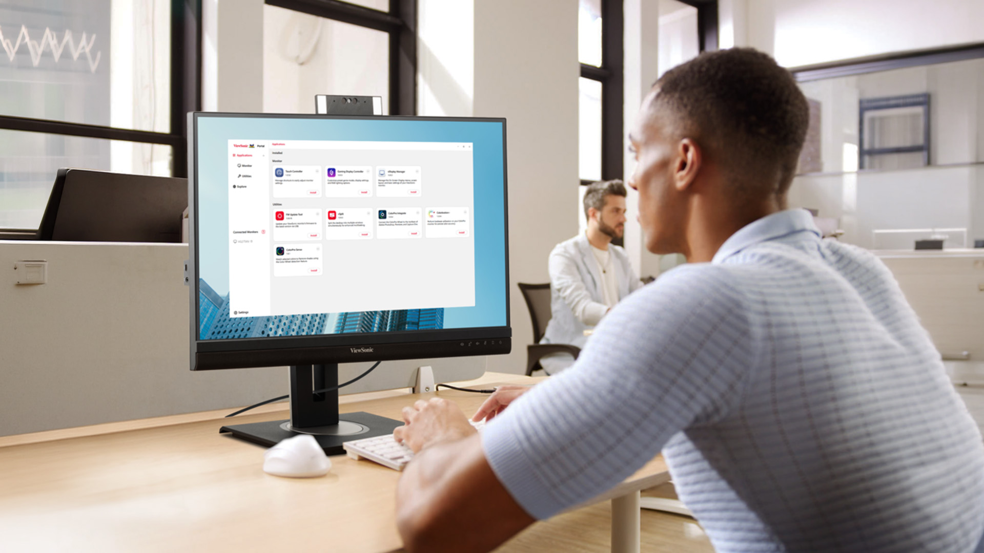 A professional sitting at an office desk using the ViewSonic Display Portal software on a monitor.