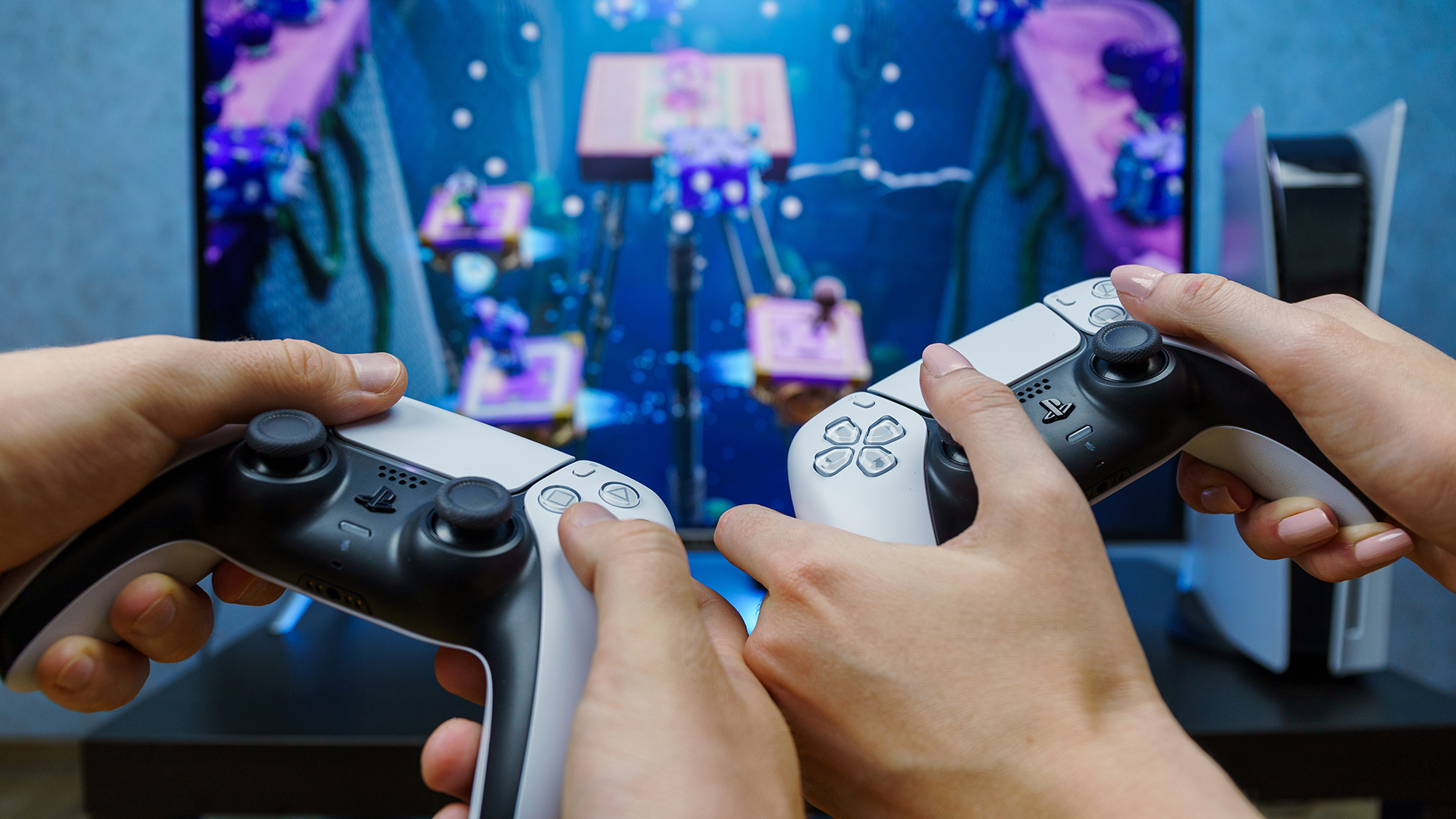 Two people holding PS5 DualSense controllers playing co-op game.