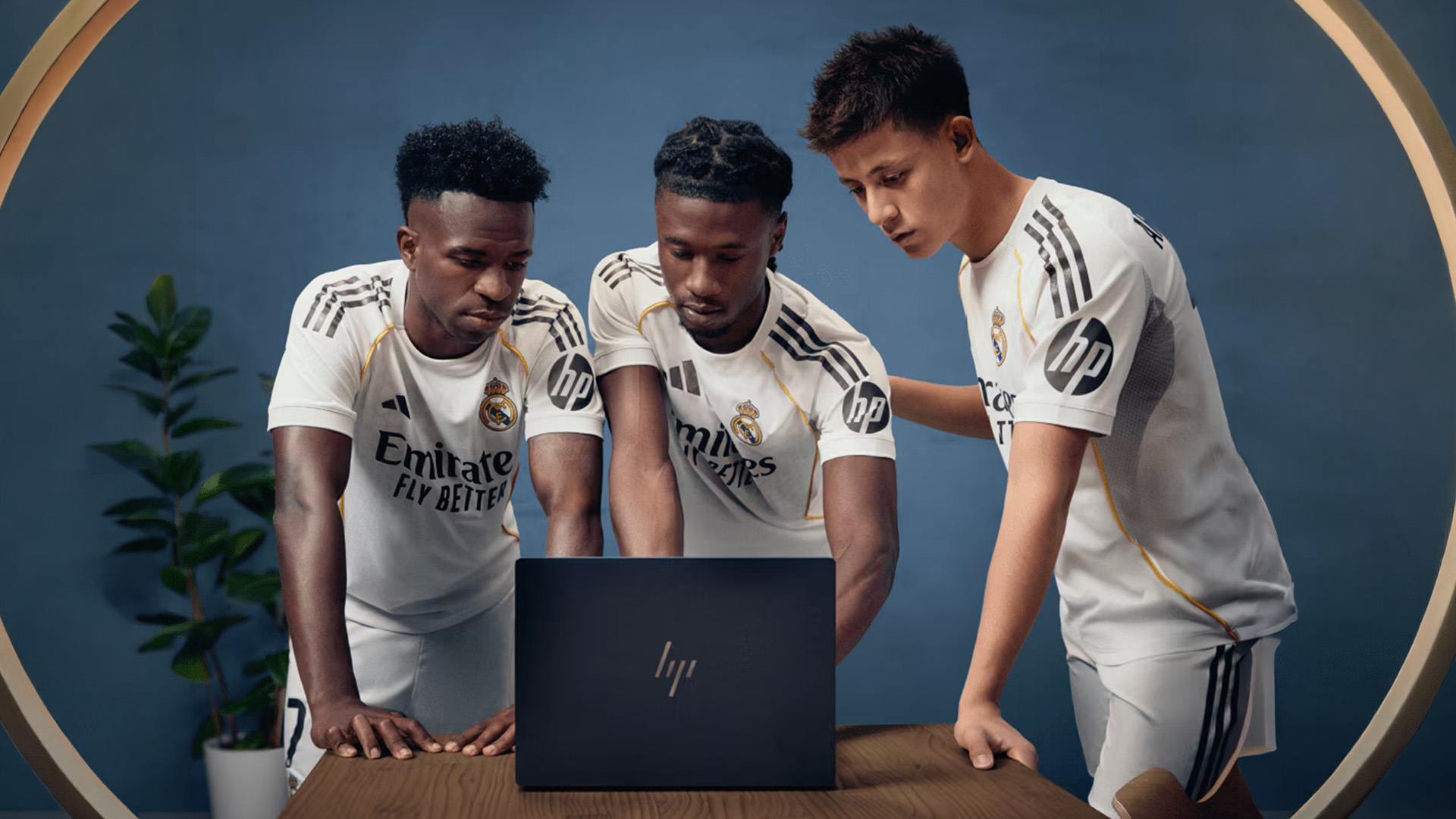 Real Madrid football players gathered around looking at an open HP laptop.