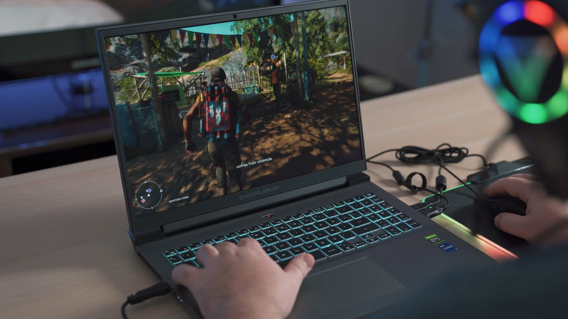A user testing gameplay on a refurbished gaming laptop with an illuminated keyboard on a wooden desk.